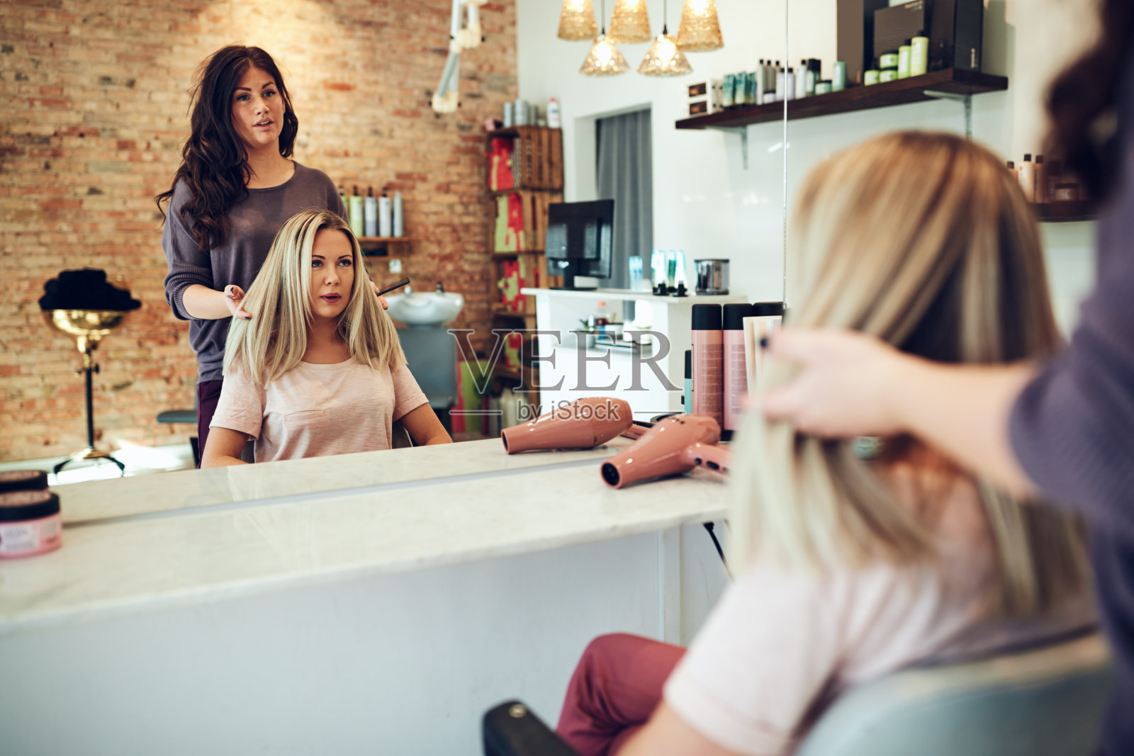 一位年轻女子正在和美容院的发型师讨论她的头发照片摄影图片