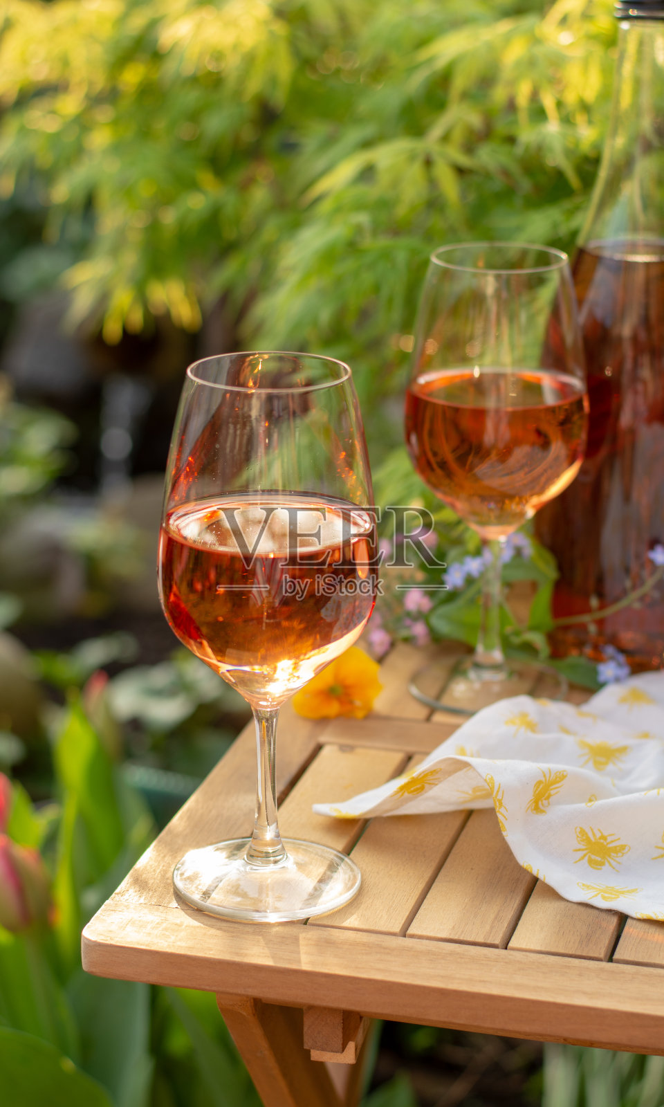 在阳光明媚的日子里，在花园的露天露台上，用玻璃杯盛着冷玫瑰葡萄酒照片摄影图片