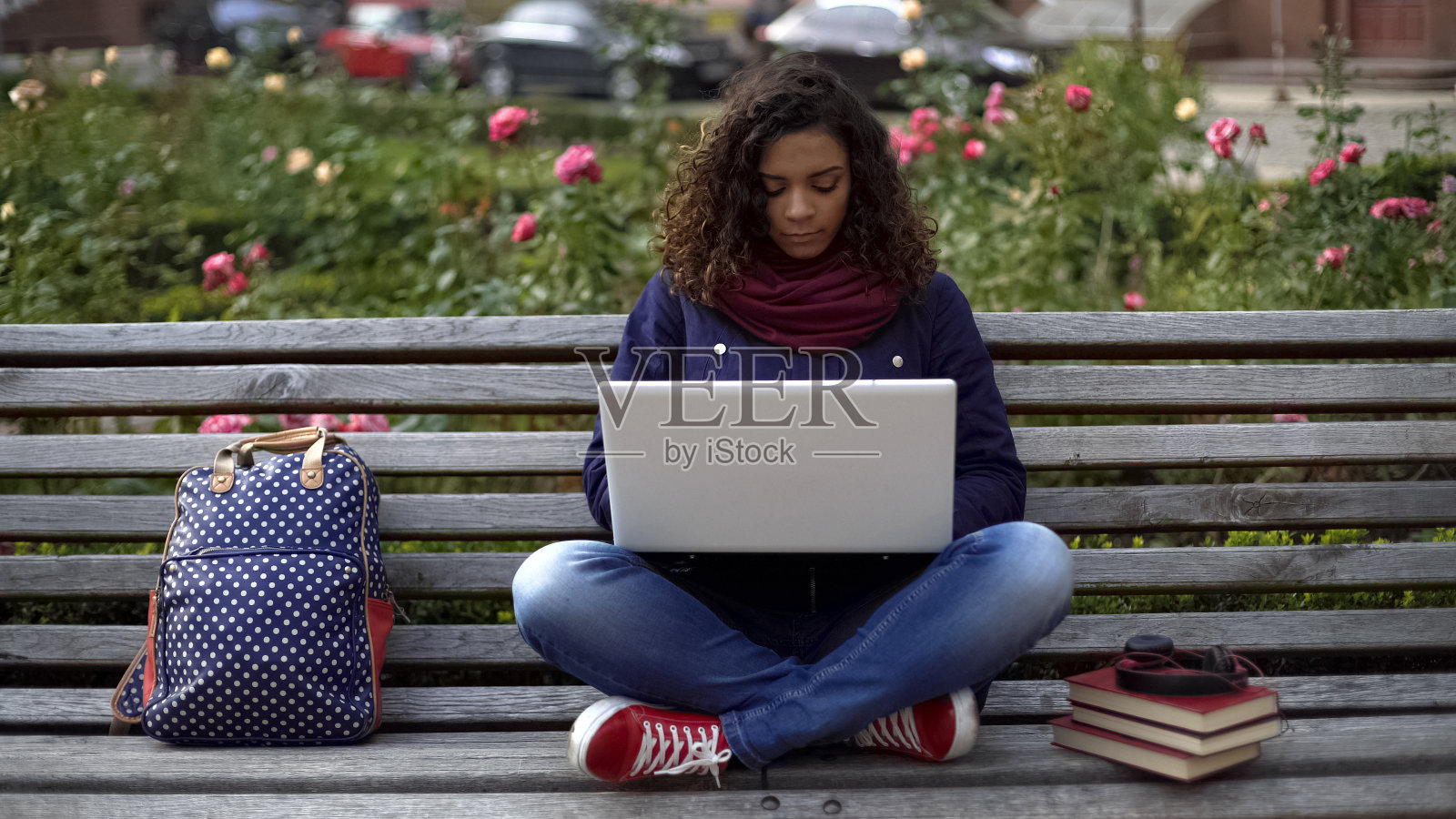 年轻的女学生坐在长凳上，带着笔记本电脑在户外集中学习照片摄影图片