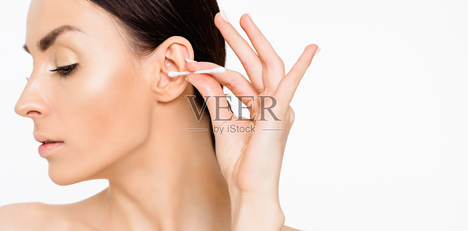 一个女人正在用耳棒清洁她的耳朵照片摄影图片