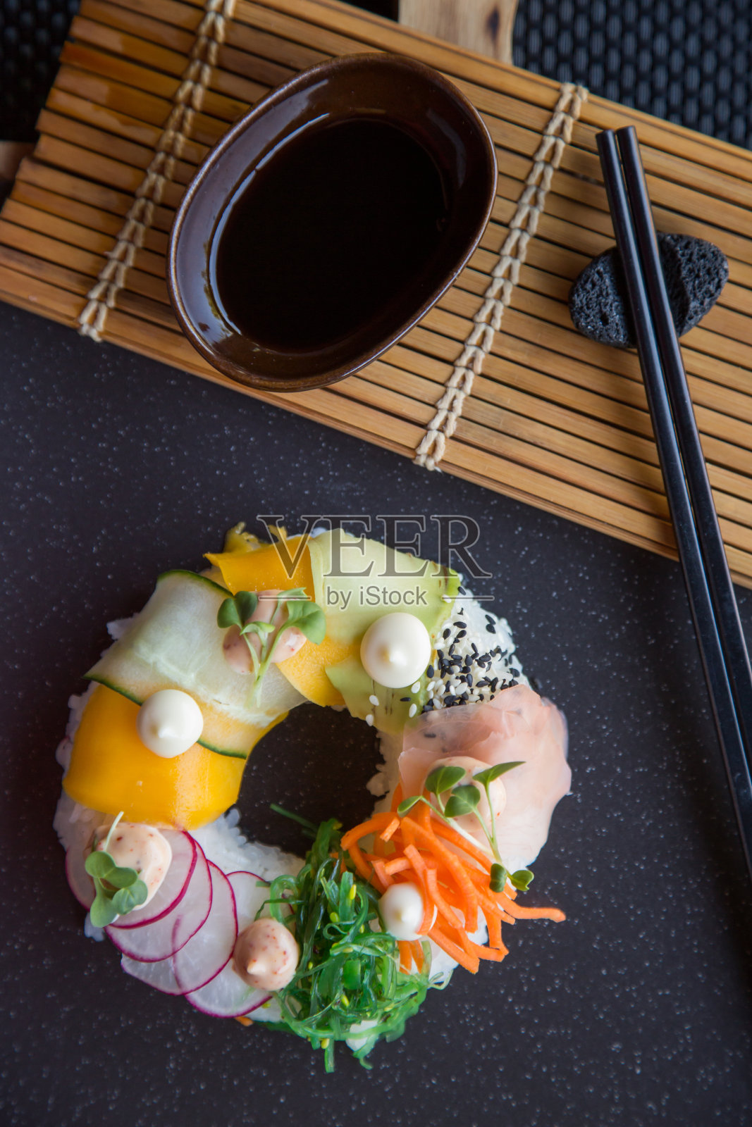素菜寿司甜甜圈，配上姜、鳄梨、黄瓜、韭菜，放在石板上。Sushi-food混合动力车的趋势。高端美食照片摄影图片