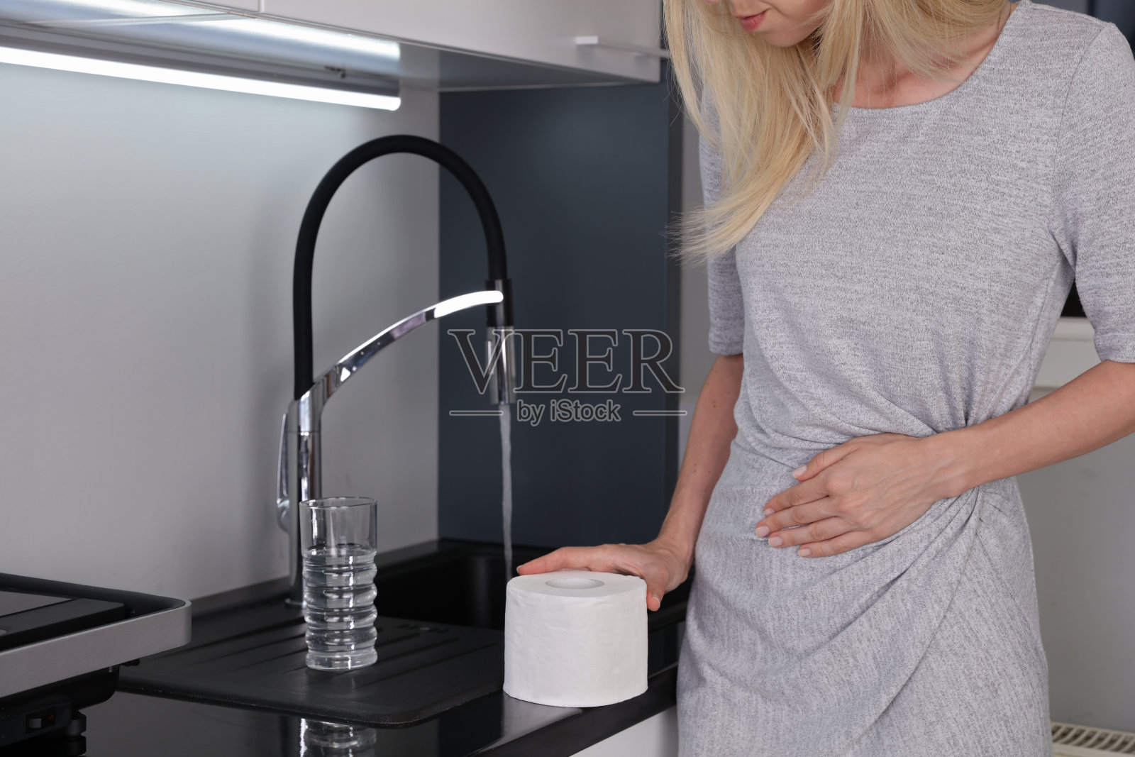 妇女饮用自来水后胃痛和腹泻。细菌学上适合的水，环境卫生和卫生概念。照片摄影图片