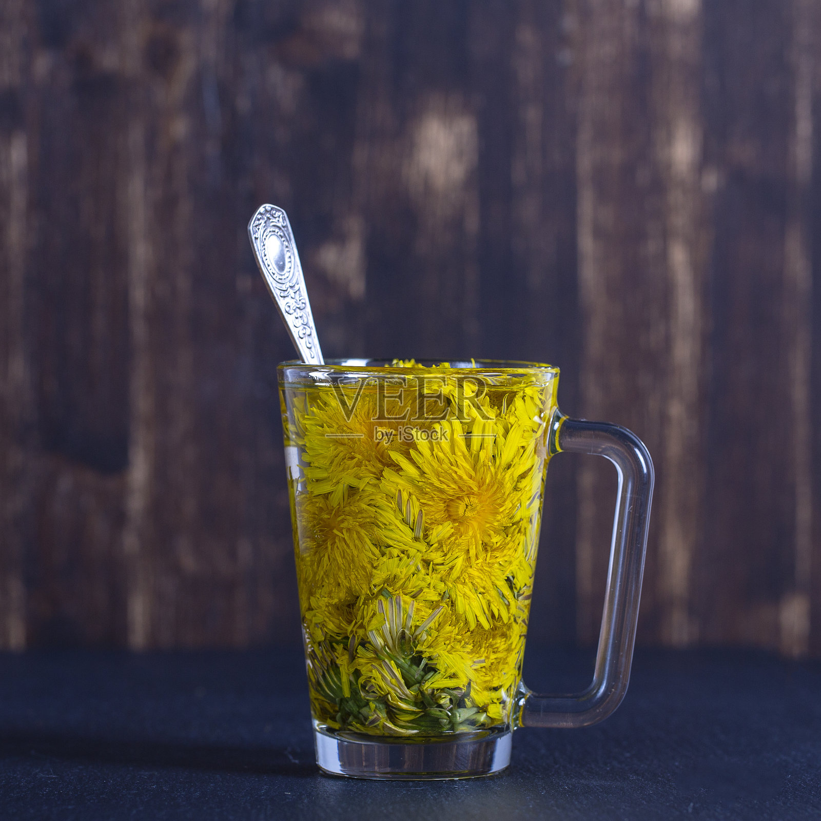 蒲公英黄花茶饮在玻璃杯中。健康饮食的概念照片摄影图片