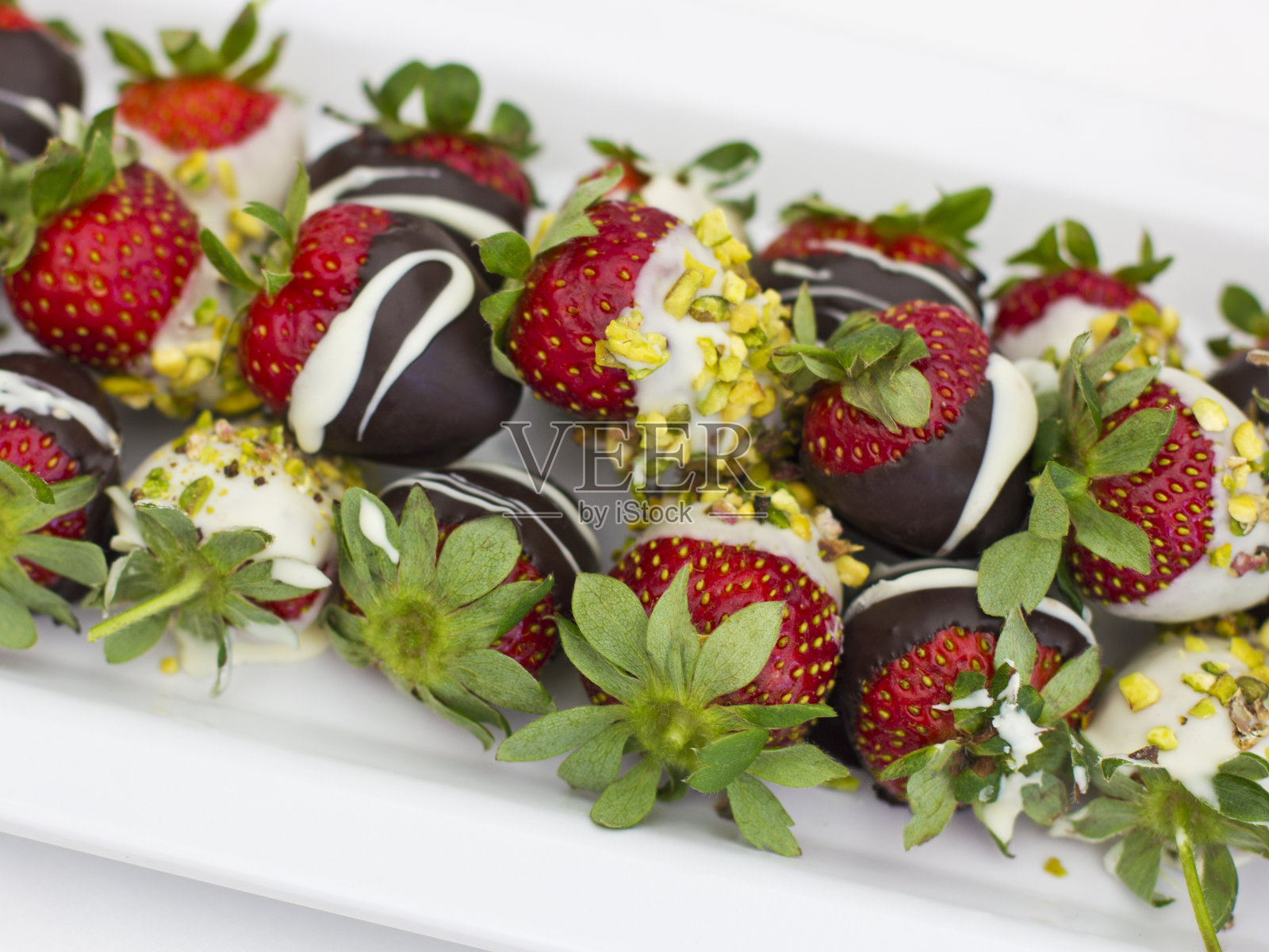 新鲜的巧克力草莓和开心果白盘子照片摄影图片