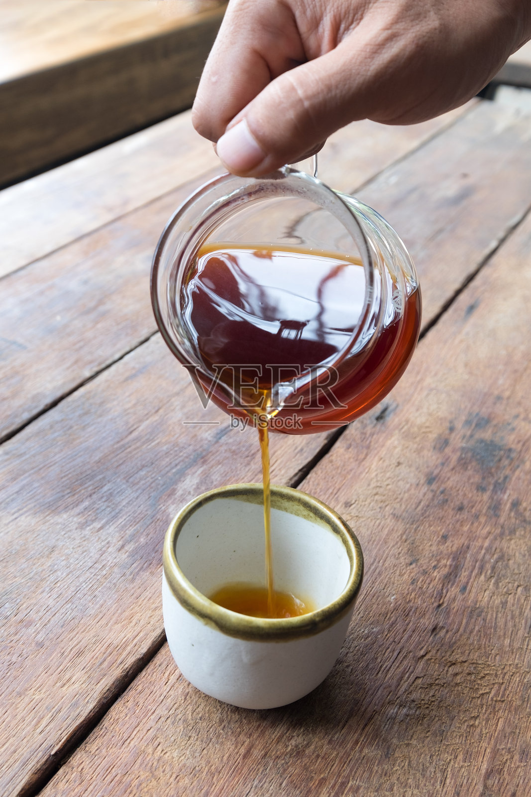 咖啡滴在咖啡壶里，倒进咖啡店木桌上的陶瓷杯里照片摄影图片