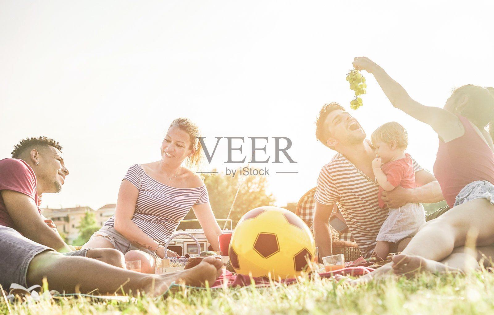 快乐的家庭吃新鲜的水果和一起欢笑在城市公园野餐-儿子父母和朋友一起在阳光明媚的周末-夏天和爱的概念-集中在正确的男人的脸照片摄影图片