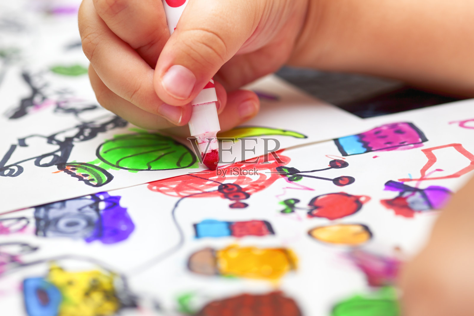 孩子用红色毡尖笔在纸上涂色小图片。照片摄影图片