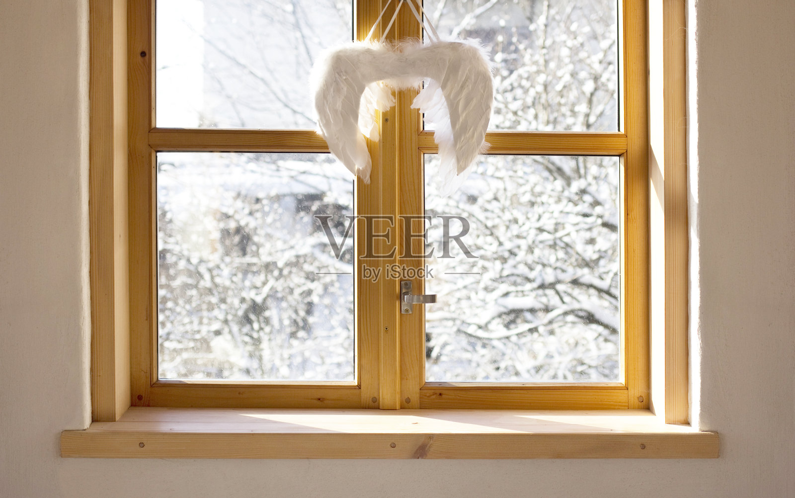 冬天的院子里透过窗户看到装饰着天使翅膀的圣诞节。照片摄影图片
