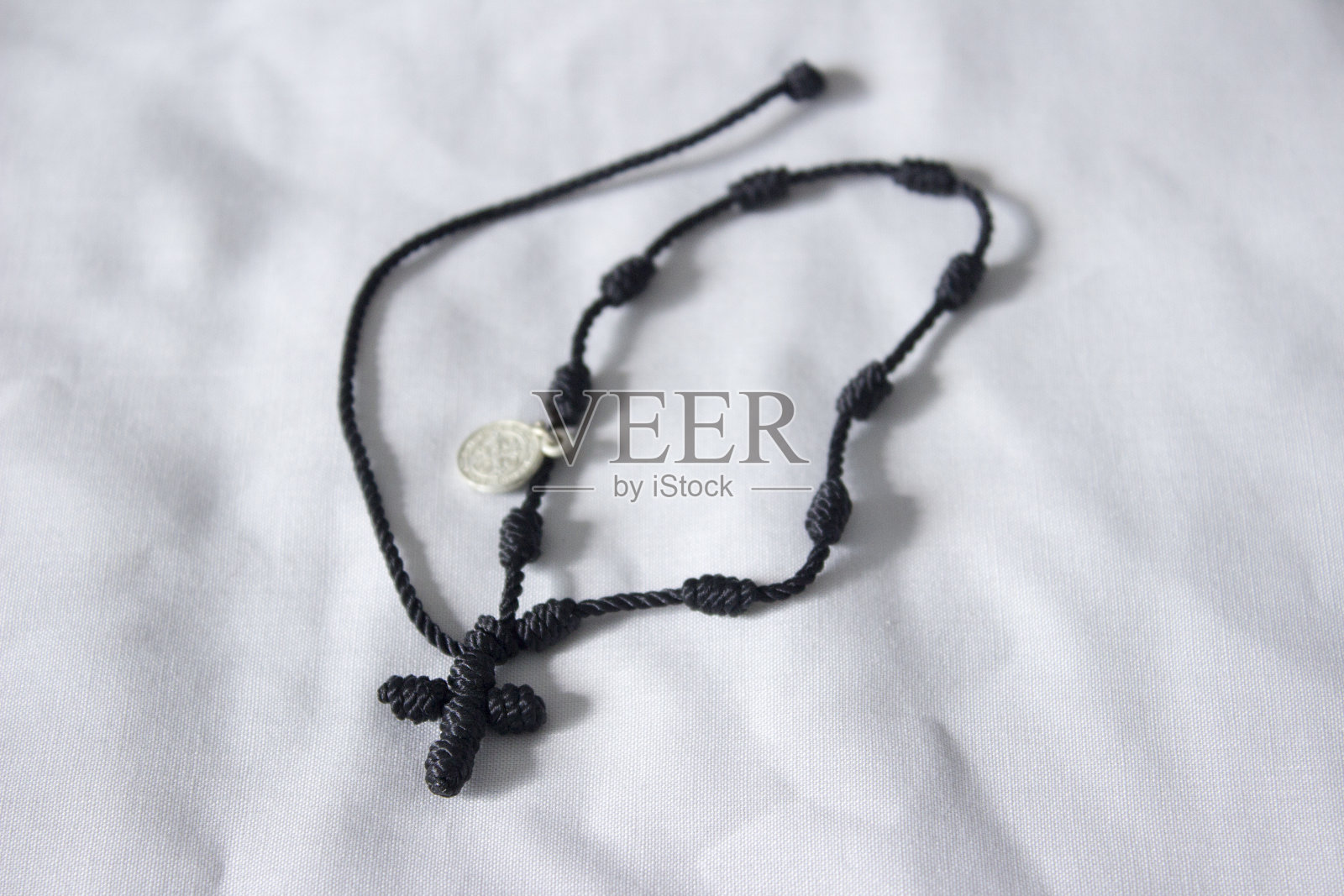 天主教黑色羊毛手链与一个小十字架。照片摄影图片
