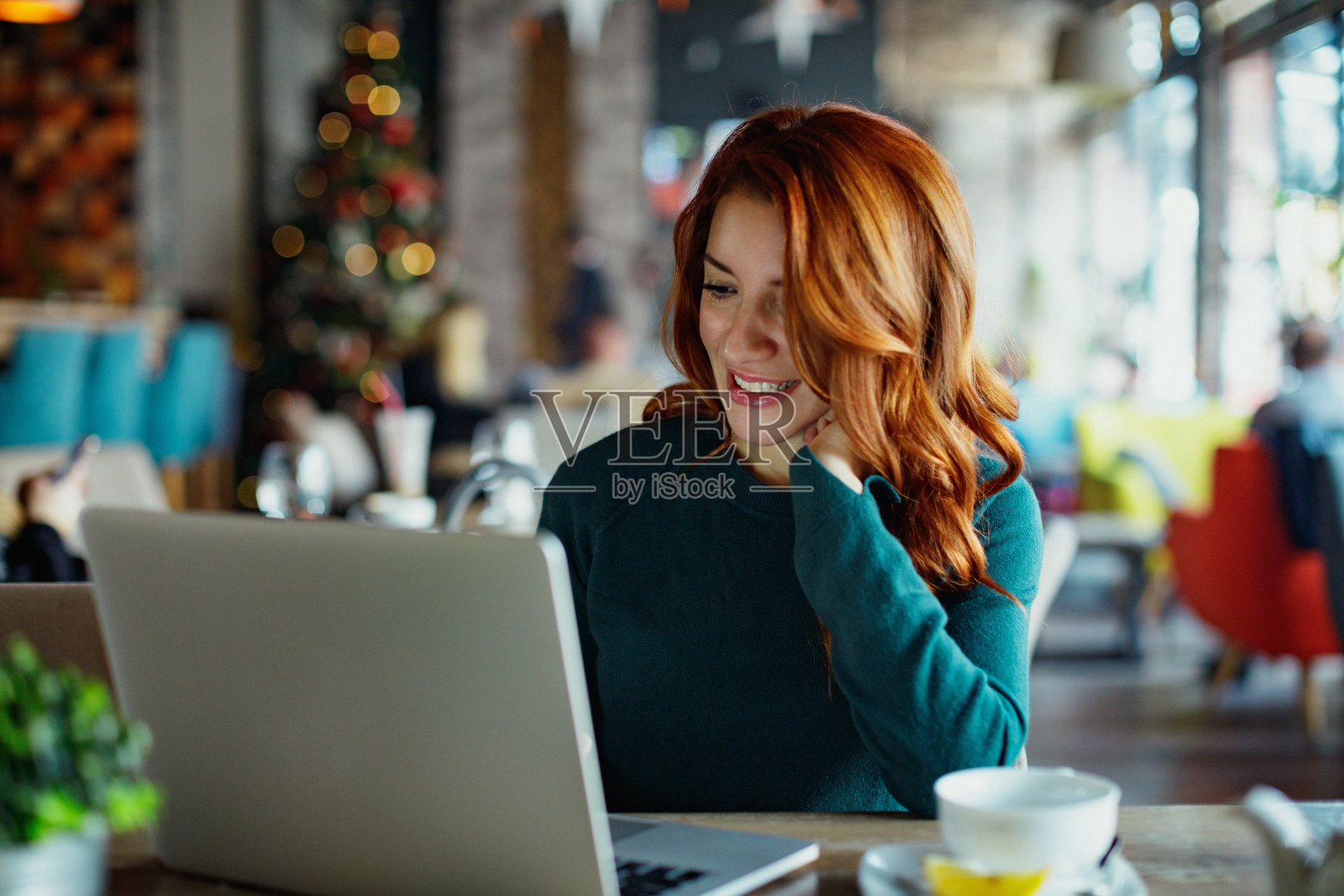 微笑的女人在咖啡馆的笔记本电脑上打字照片摄影图片