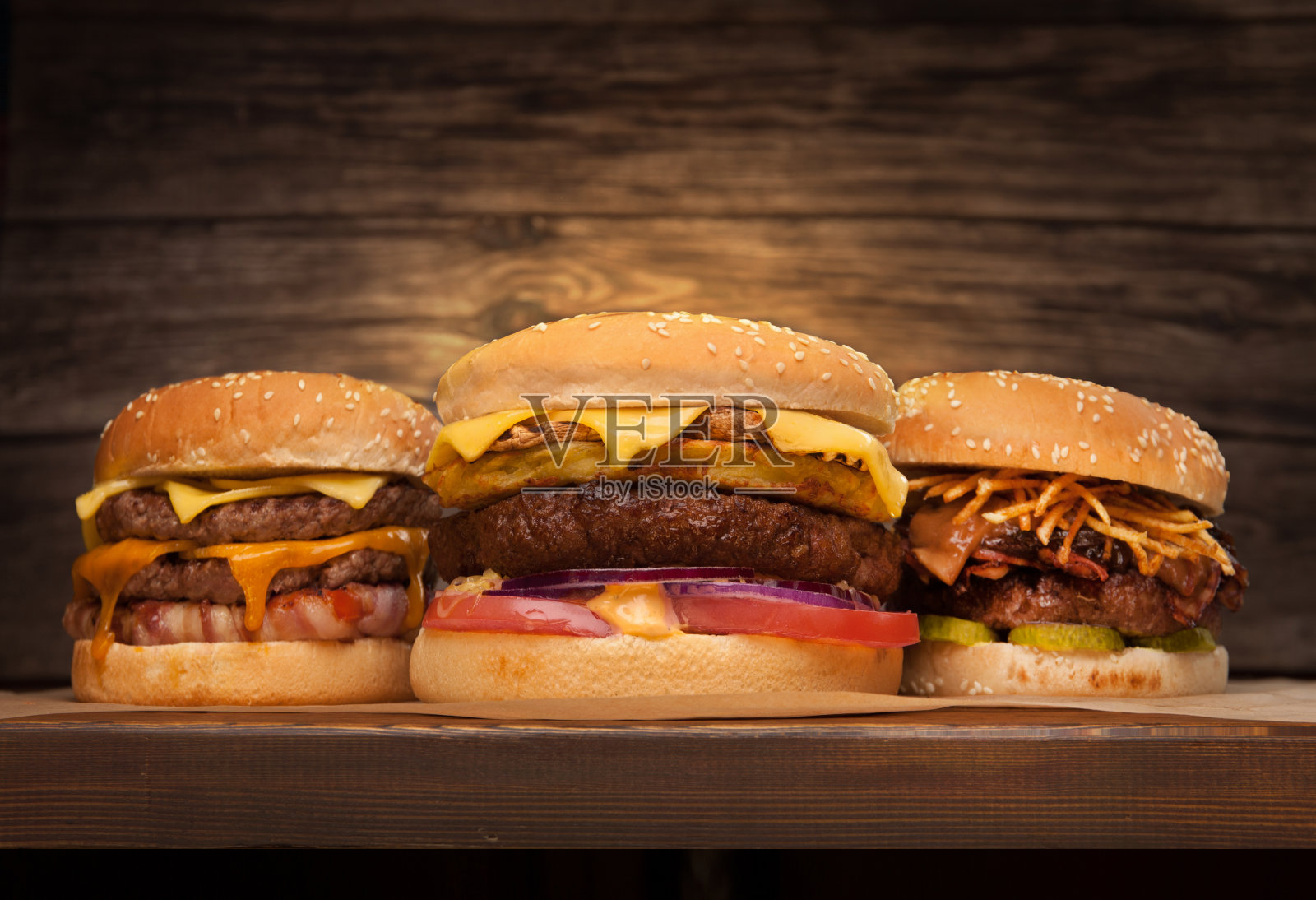 木制背景上的三个大汉堡。低角度前视图。文本复制空间照片摄影图片