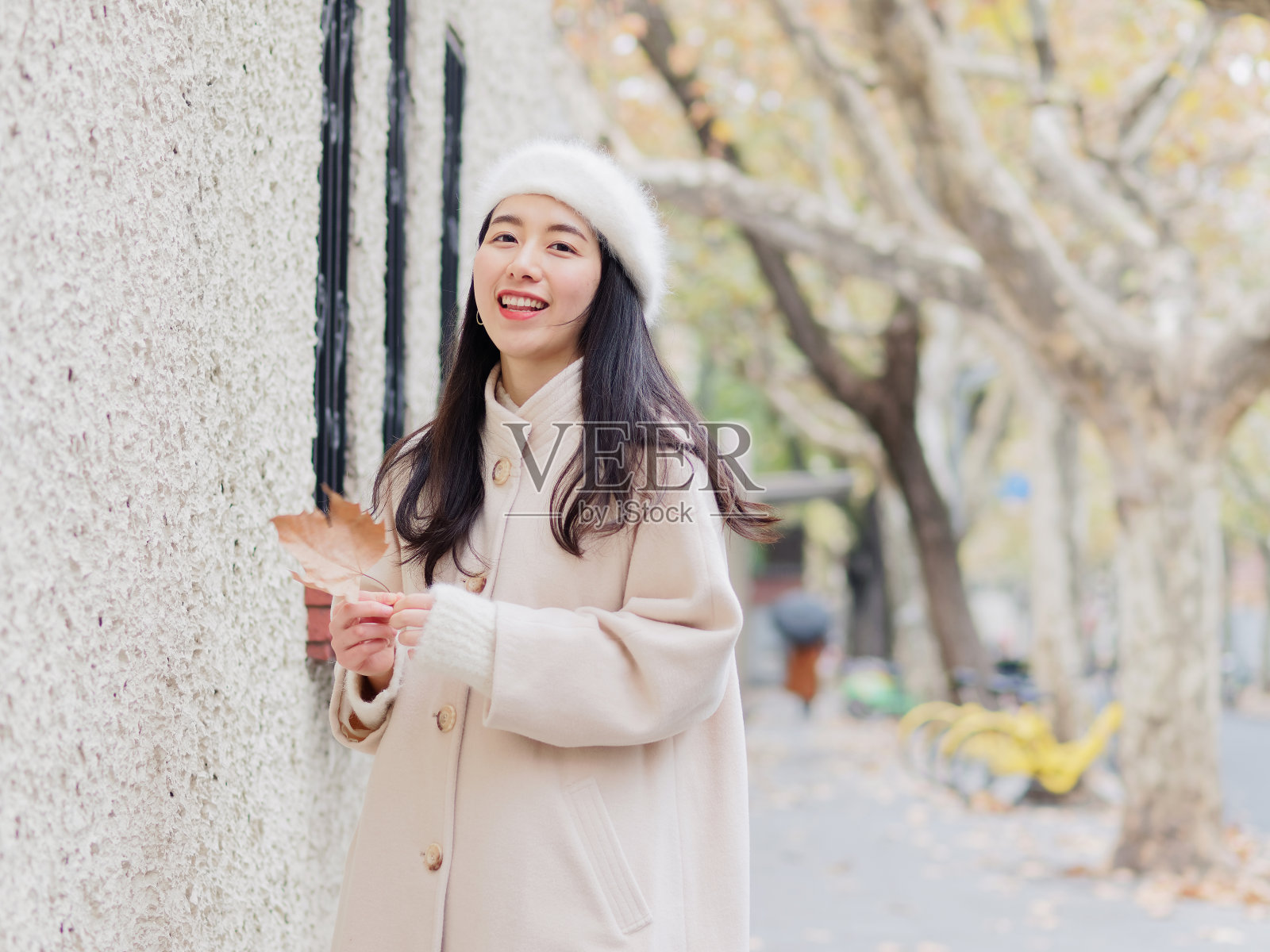在秋天的城市里，穿着白色绒毛外套的漂亮年轻女子。户外时尚写真魅力中国开朗时尚的街头淑女。情感、人、美、生活理念。照片摄影图片