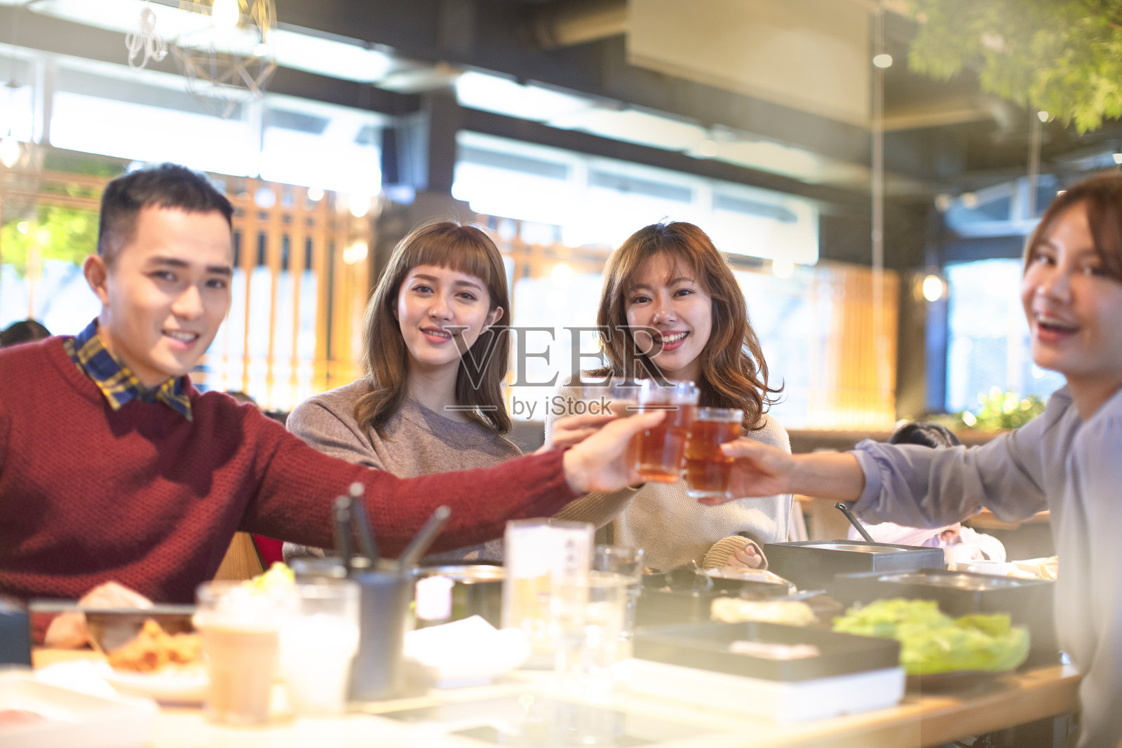 快乐的年轻人朋友们在餐馆里祝酒吃饭照片摄影图片
