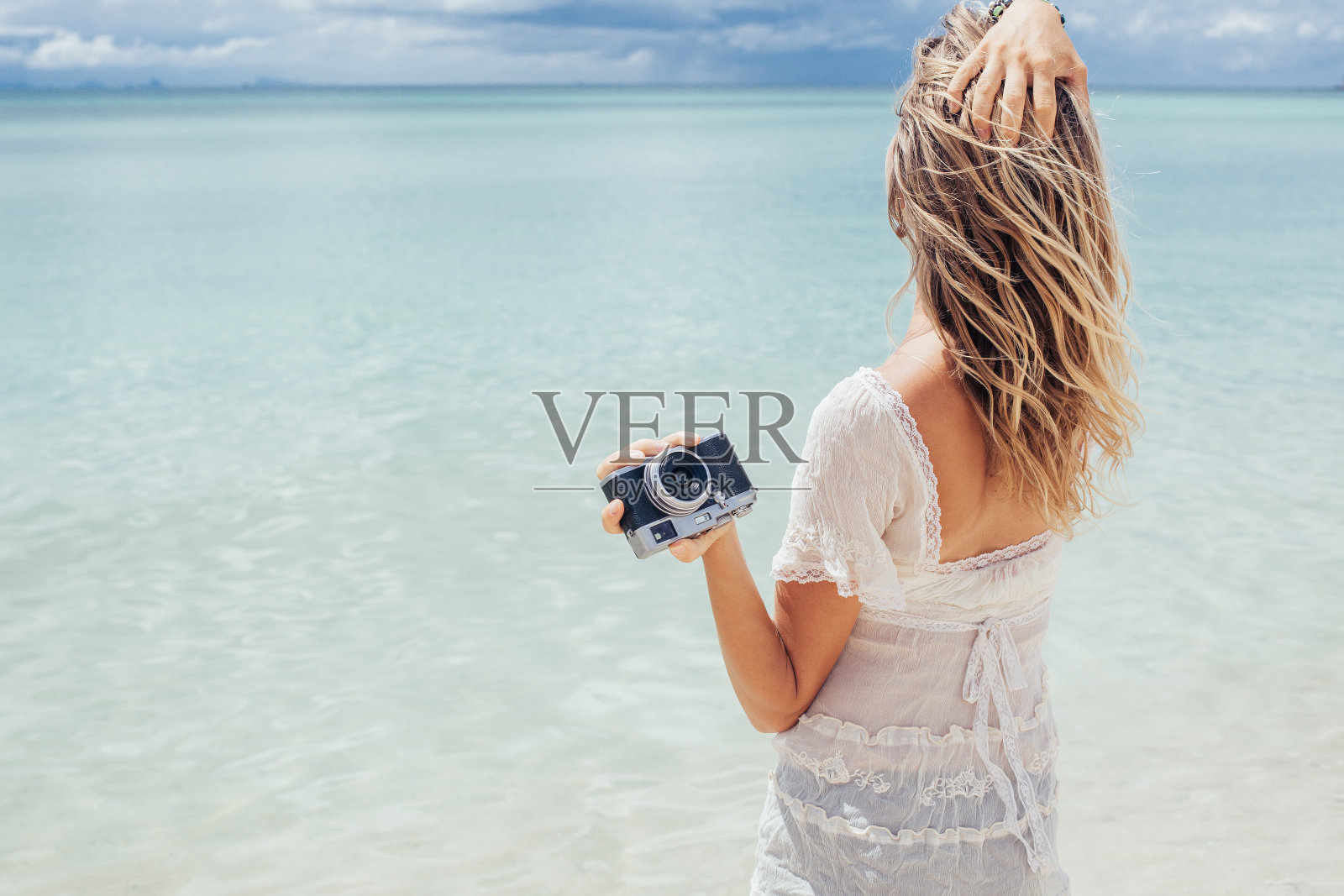 沙滩上拿着复古相机的年轻女子照片摄影图片