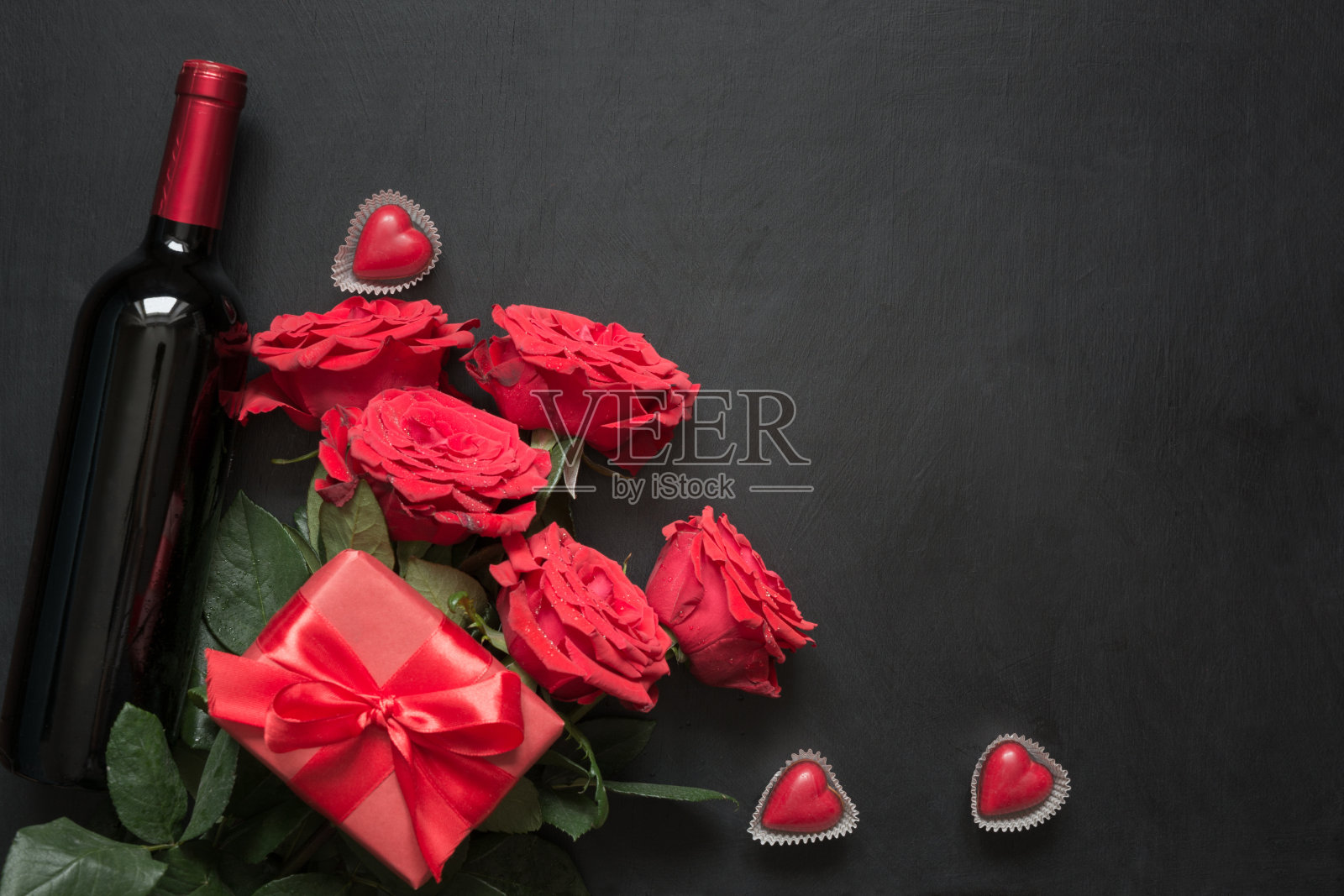 木桌上放着情人节卡片，上面有浪漫的红玫瑰、酒瓶、心形和红色礼盒。顶视图与空间。照片摄影图片