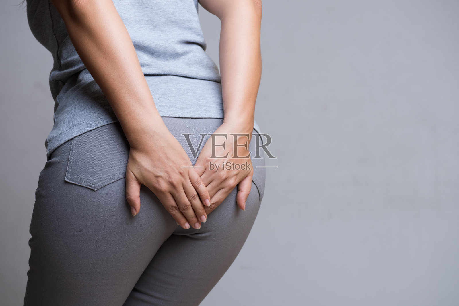 患有痔疮的妇女，因为腹痛而用手托着她的屁股。卫生保健的概念。照片摄影图片