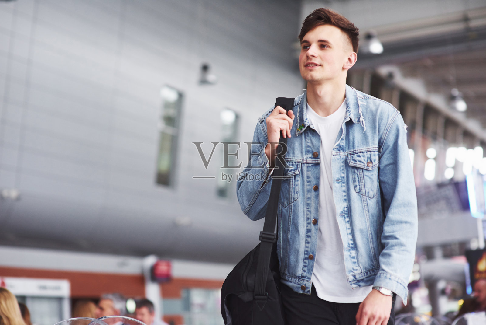 年轻英俊的男子肩上扛着包，急着去机场照片摄影图片