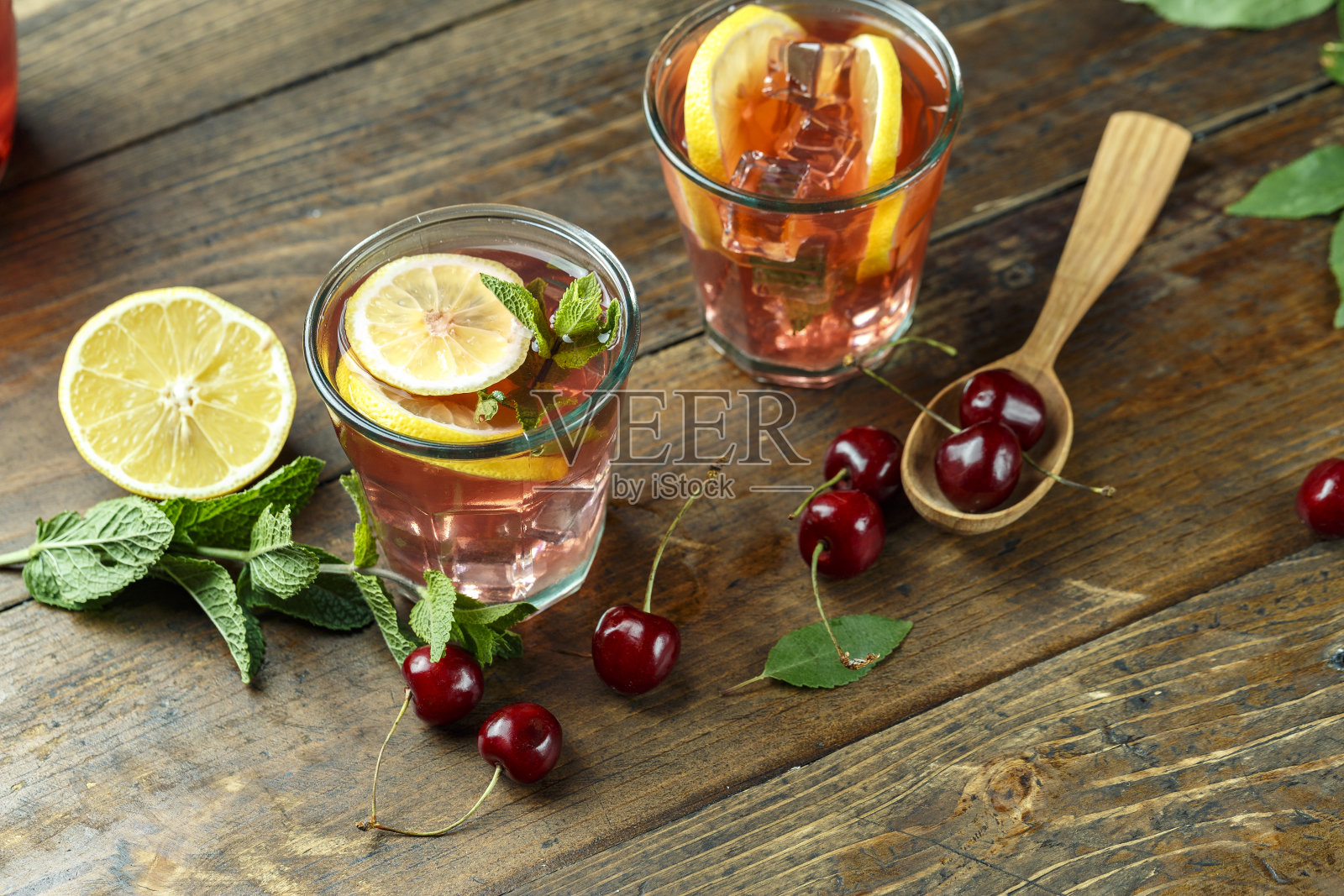 自制甜樱桃蜜饯在玻璃杯与柠檬在木背景。照片摄影图片