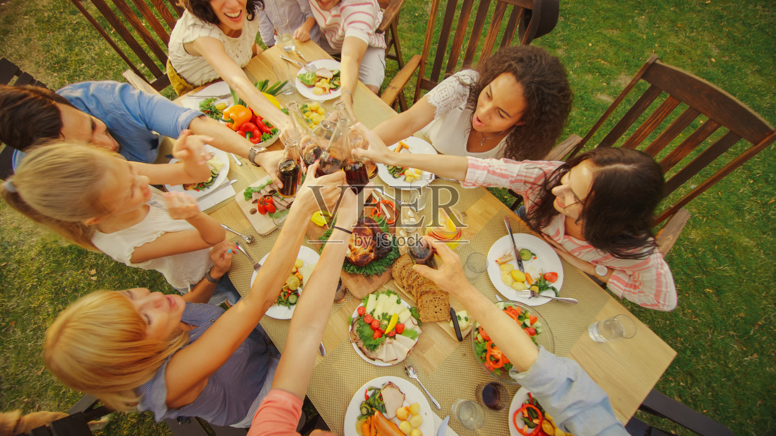 家人和朋友聚在一起举杯祝酒碰杯。家庭花园聚会庆典。自顶向下。照片摄影图片
