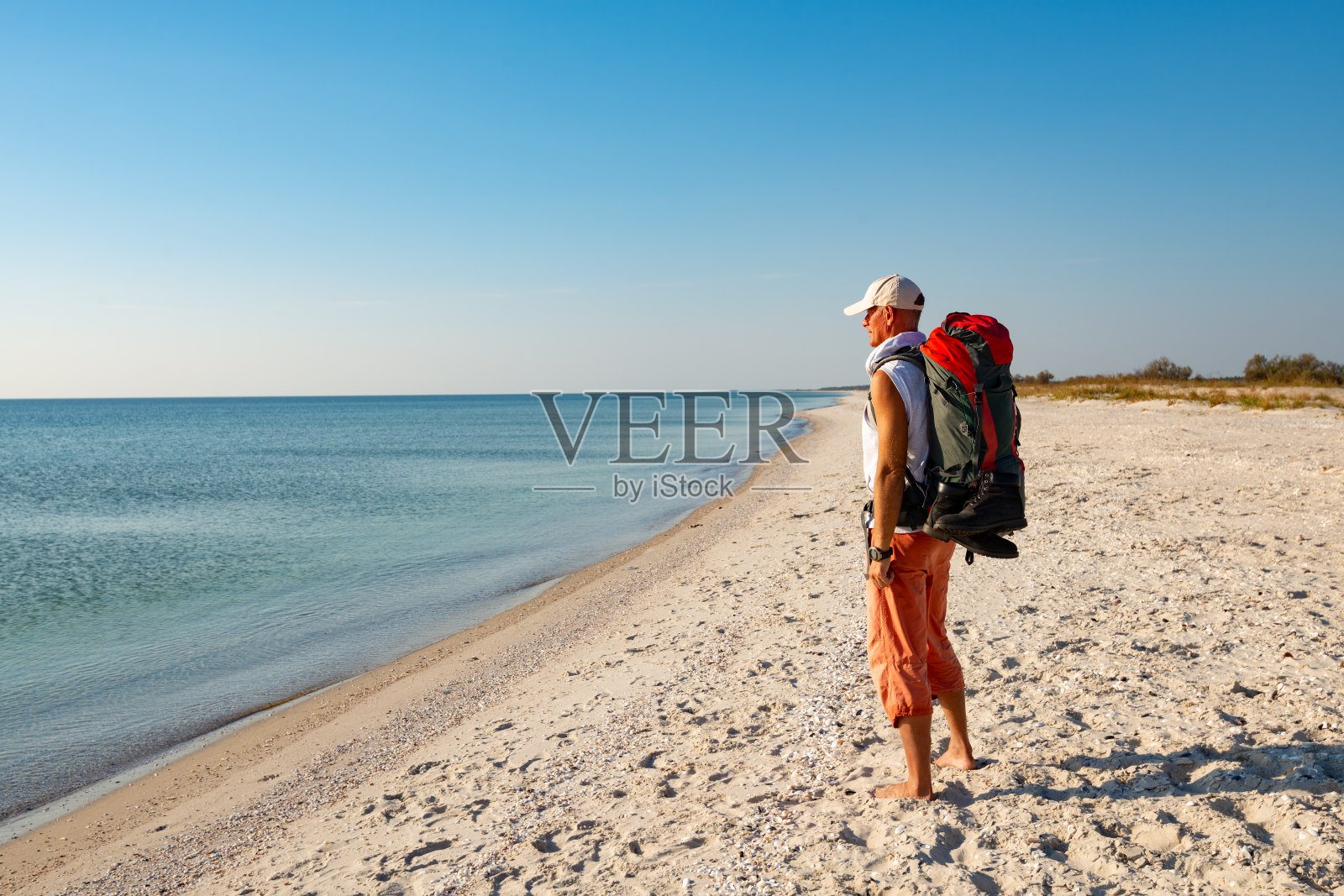 背着背包的旅行者站在荒芜的海滩上照片摄影图片