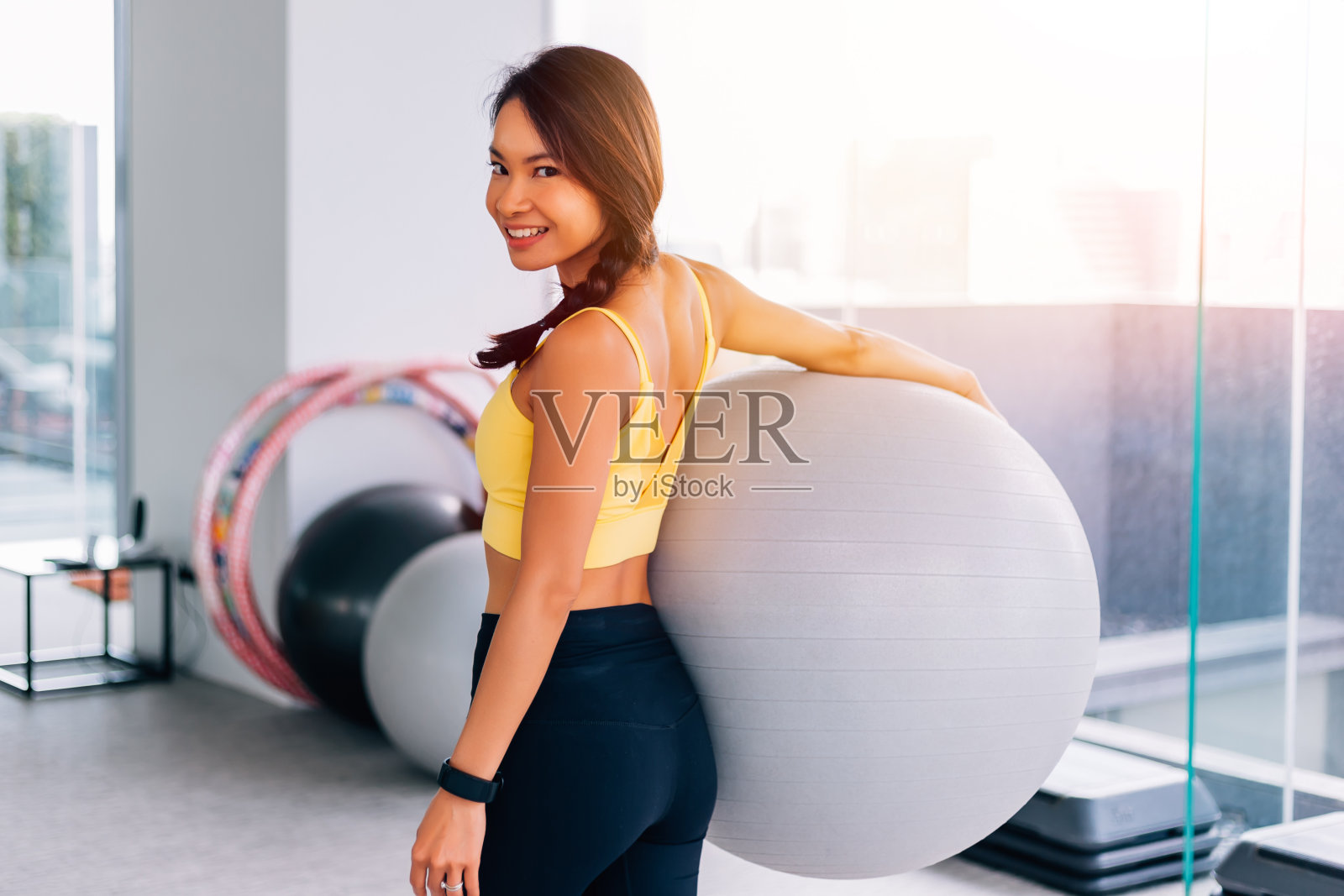 肖像年轻健康的亚洲妇女持有锻炼瑞士球和微笑的镜头。活泼的女性健身模特形象照片摄影图片