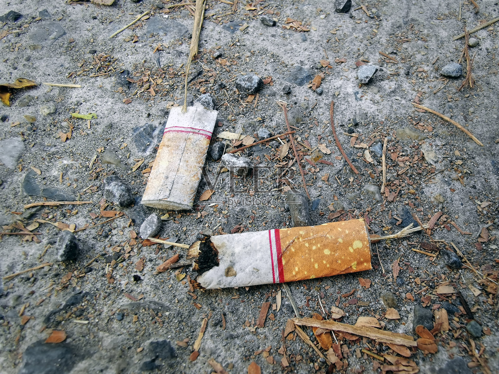 特写:地上残存的燃烧香烟照片摄影图片