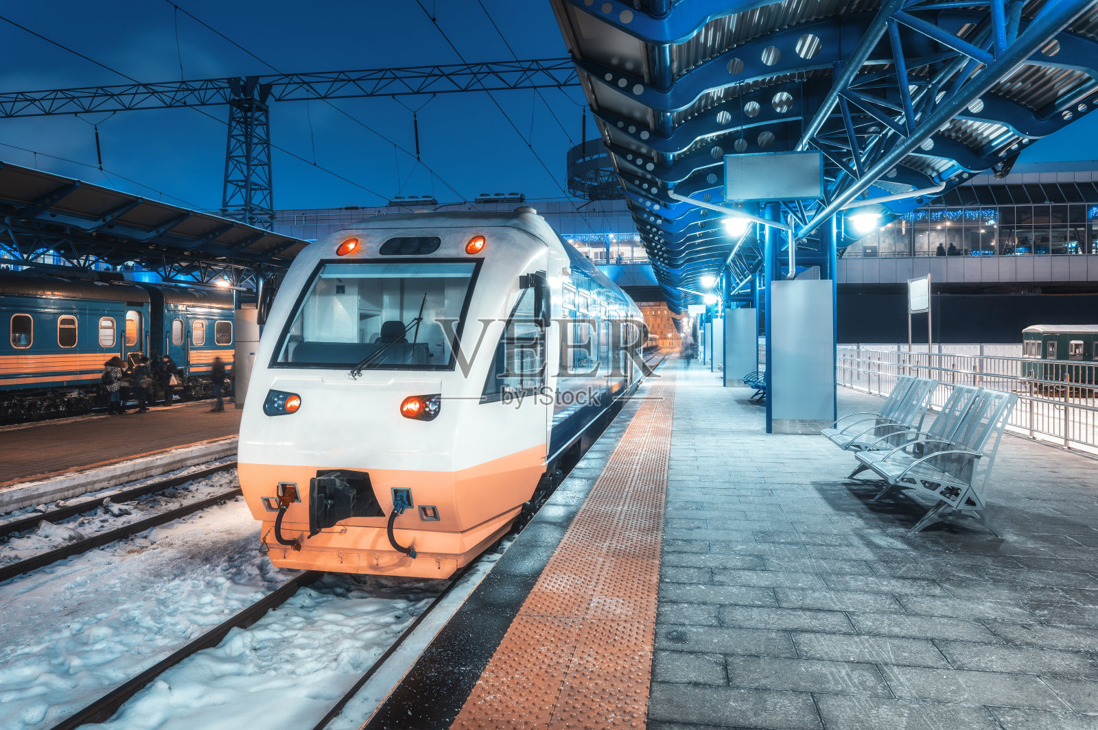 冬季夜间高铁在火车站上。城市景观与现代通勤列车在铁路月台与照明在黄昏。城际交通工具。客运铁路旅行照片摄影图片