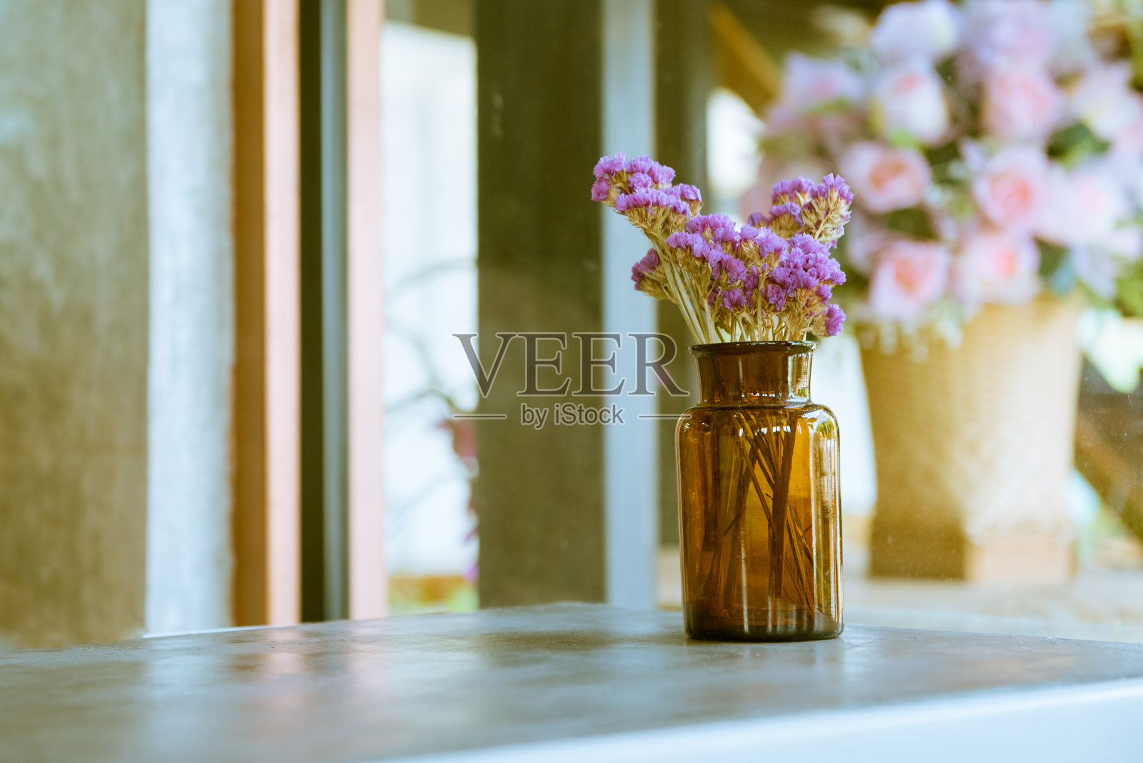 在一个复古复古的咖啡馆里，棕色的玻璃瓶和干粉色和紫色的花放在桌子上，白色和木制的面板背景照片摄影图片