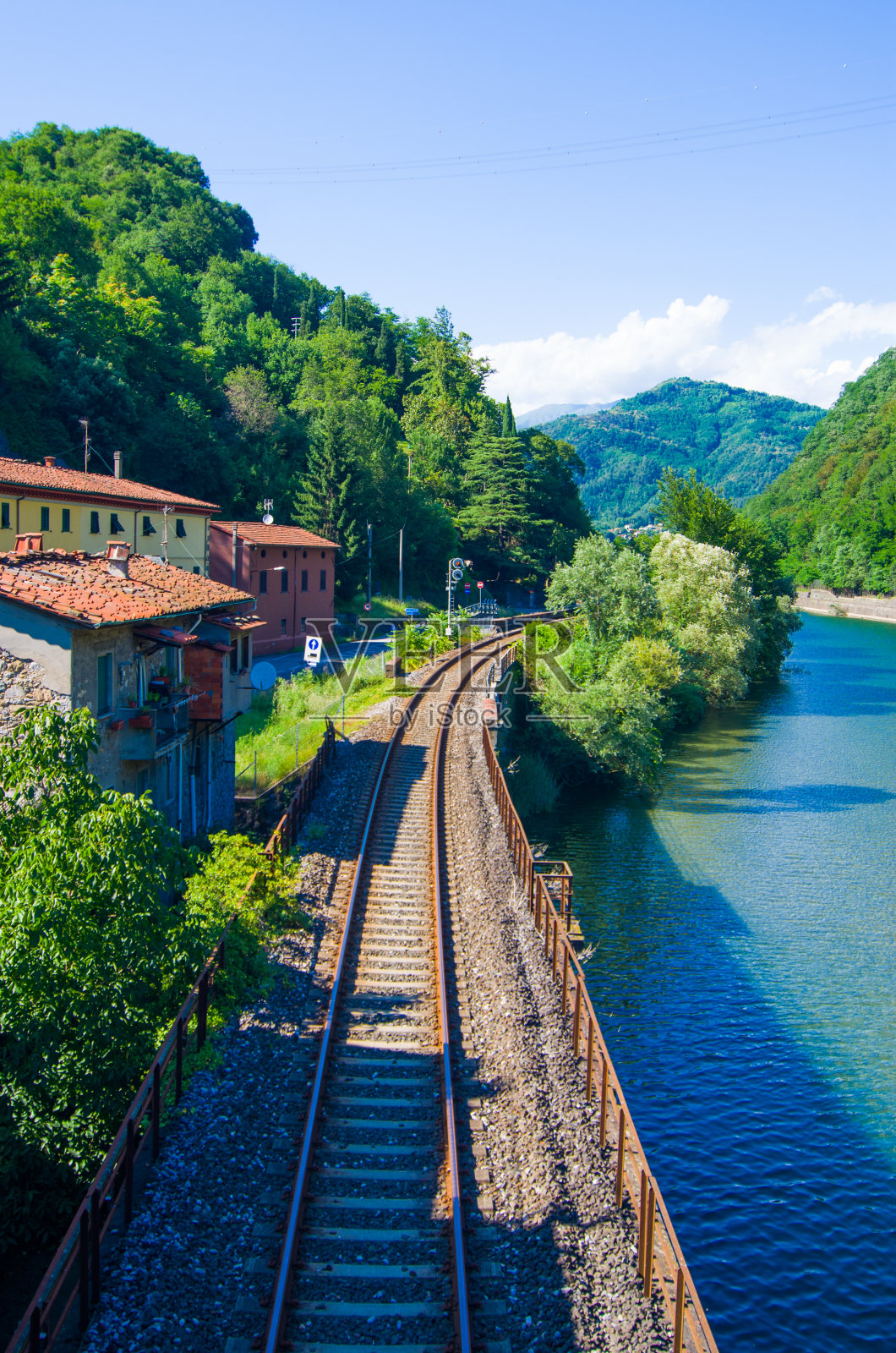 铁路沿着蓝色的湖在绿色的山照片摄影图片