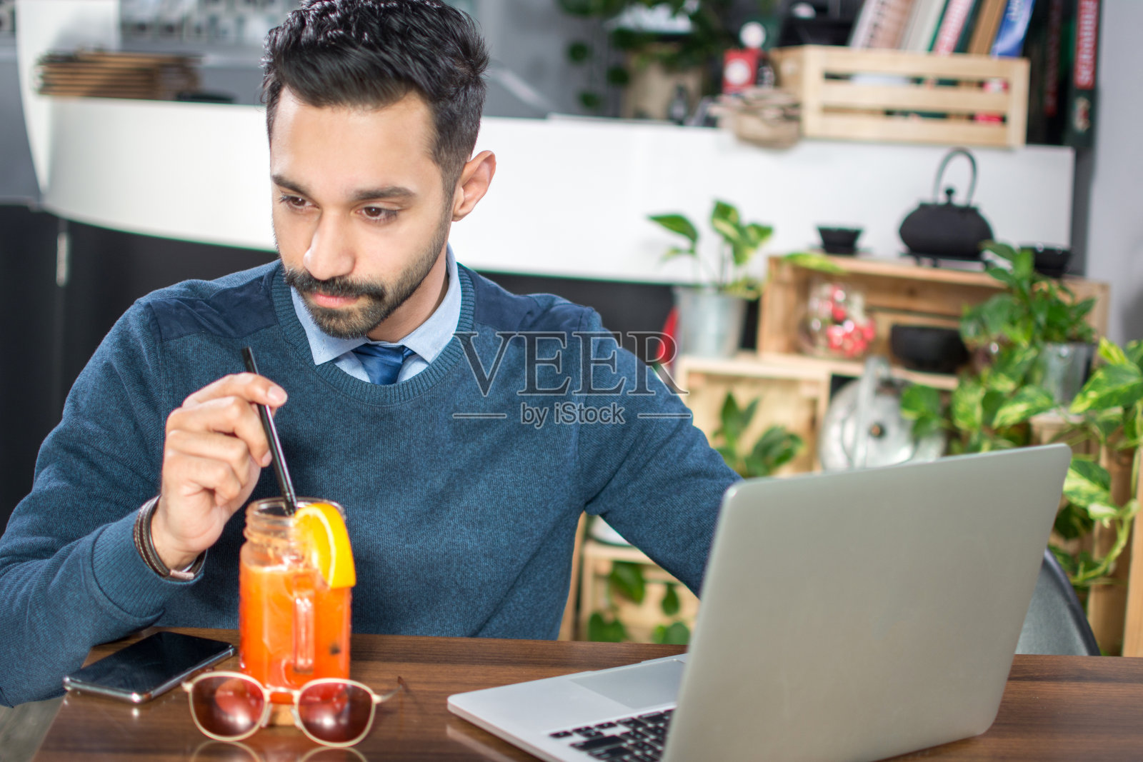 年轻的商人用笔记本电脑在办公室喝着鸡尾酒照片摄影图片
