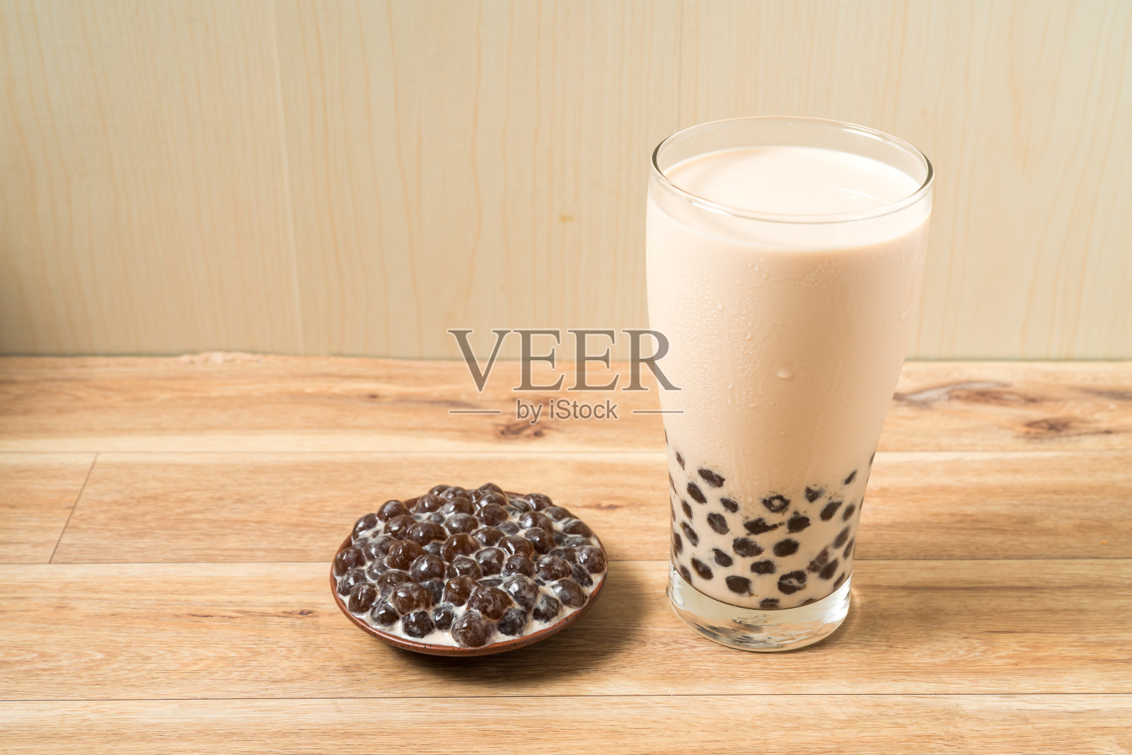 一杯珍珠奶茶(也叫珍珠奶茶)和一盘在木制背景上的木薯球。珍珠奶茶是台湾最具代表性的饮品。台湾的食物。与复制空间。照片摄影图片