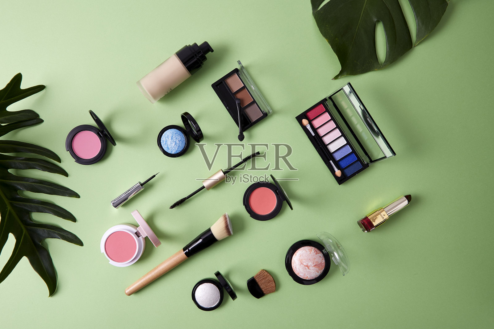 平铺彩妆用粉彩纸将美容产品排列在绿色背景上，有机彩妆的概念照片摄影图片