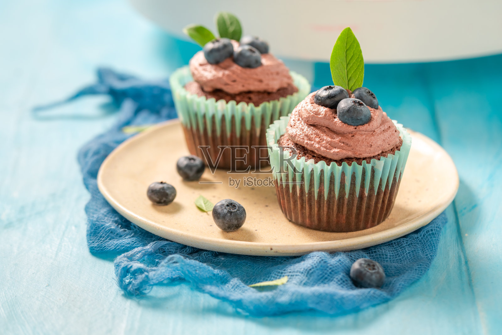 蓝莓松饼和巧克力奶油放在蓝色的桌子上照片摄影图片