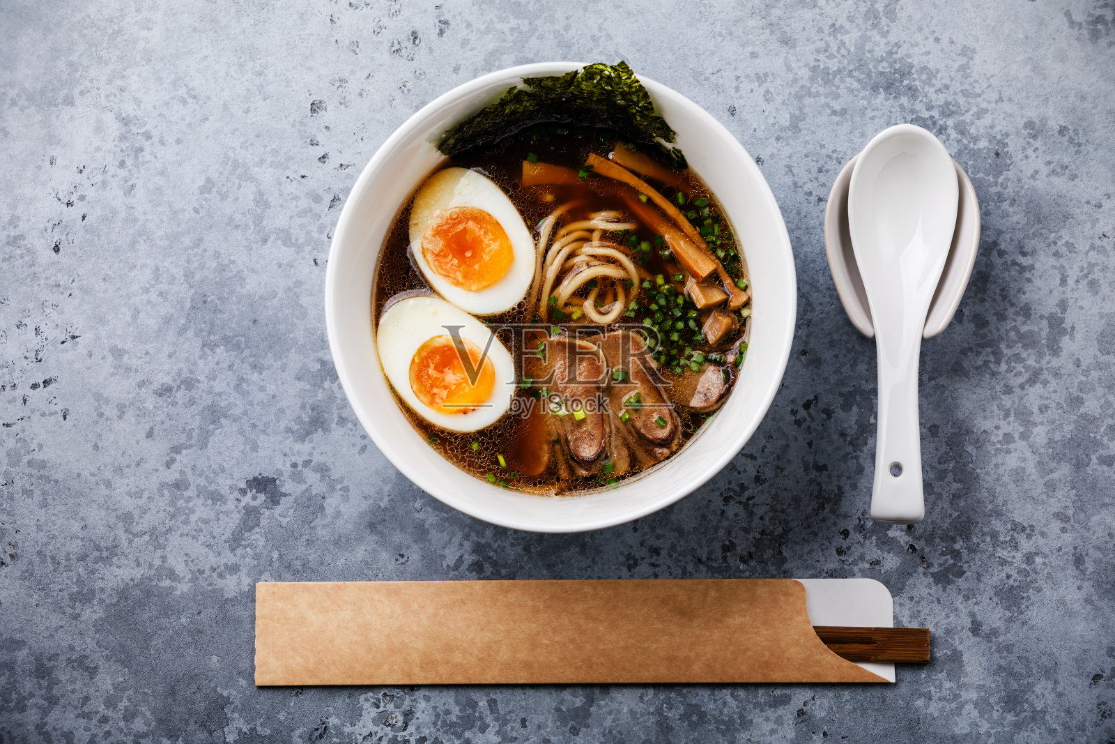 亚洲拉面肉汤牛肉舌肉和Ajitama腌制鸡蛋在碗混凝土背景照片摄影图片