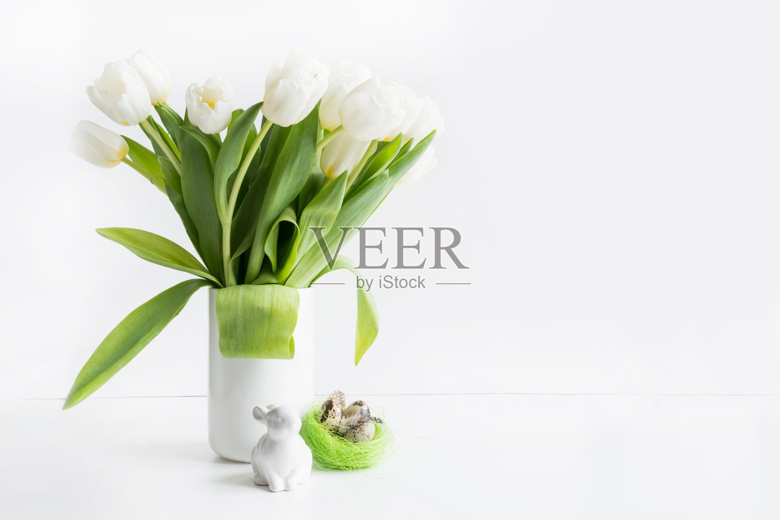 复活节。花瓶里的白色郁金香，白色的兔子和鸡蛋。照片摄影图片