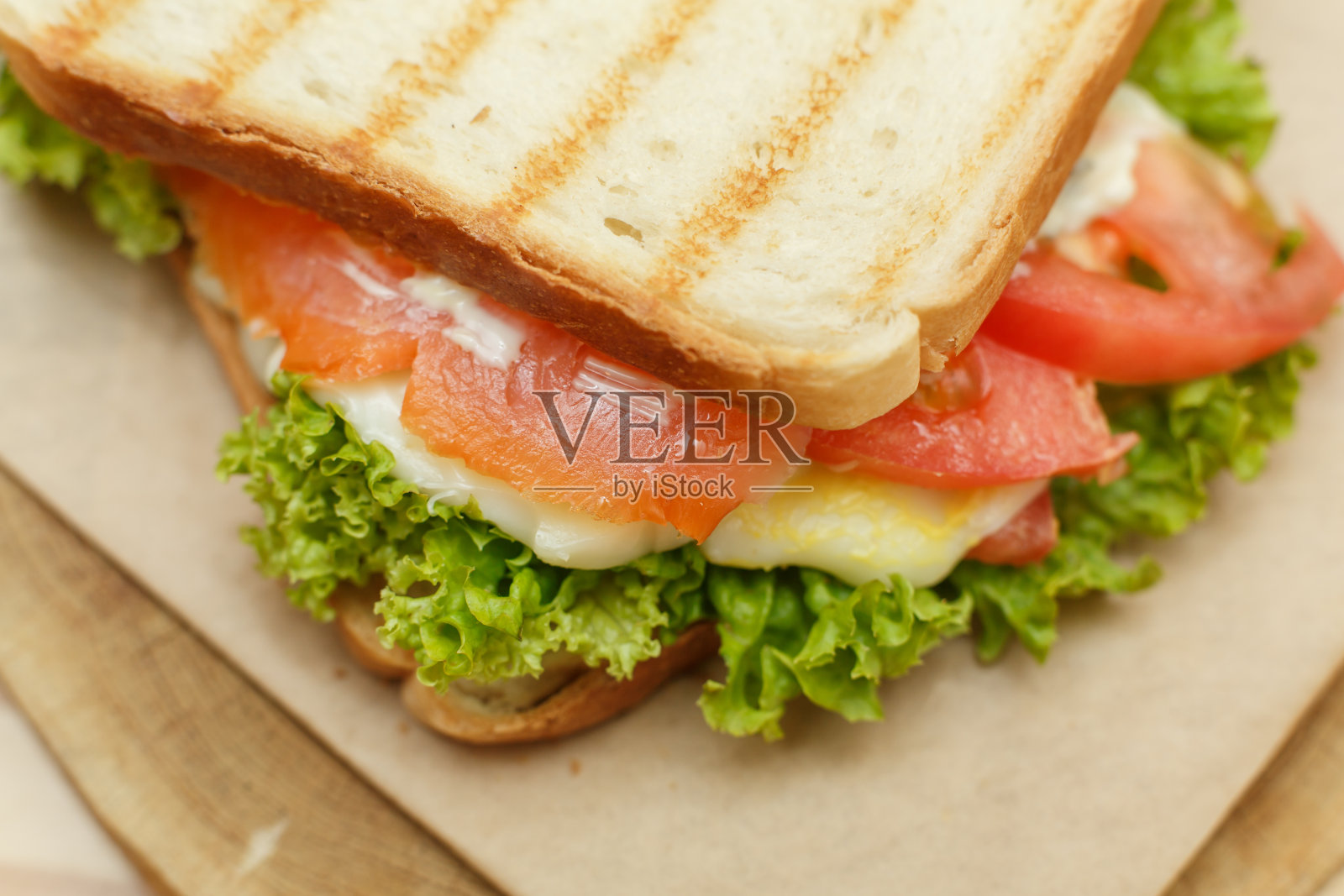 特写多汁的三明治与培根，新鲜蔬菜，绿色沙拉和烧烤后的黑线照片摄影图片