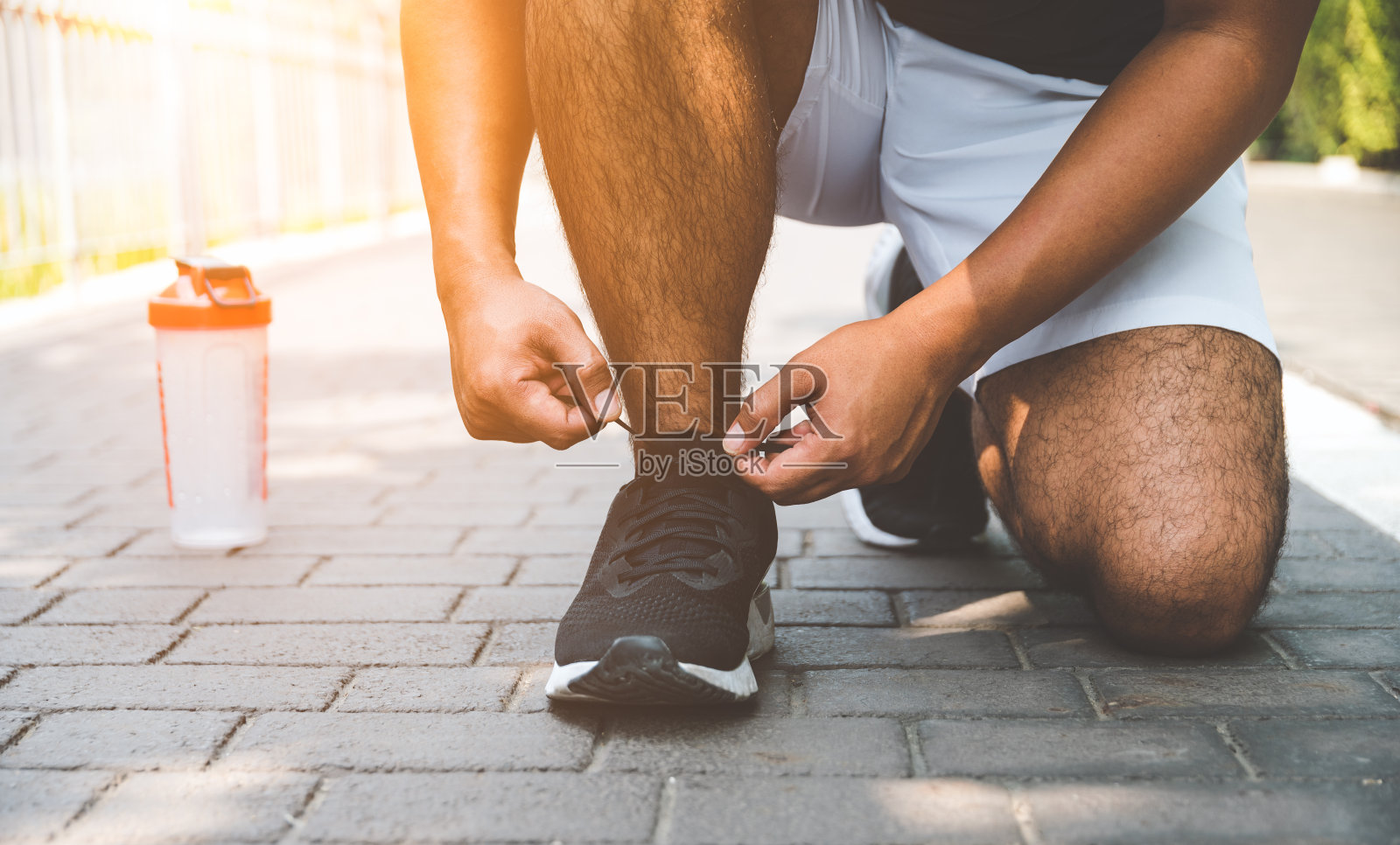 年轻的跑步者在跑道上系鞋带准备比赛。健康健身，锻炼，运动，生活方式和运动概念。照片摄影图片