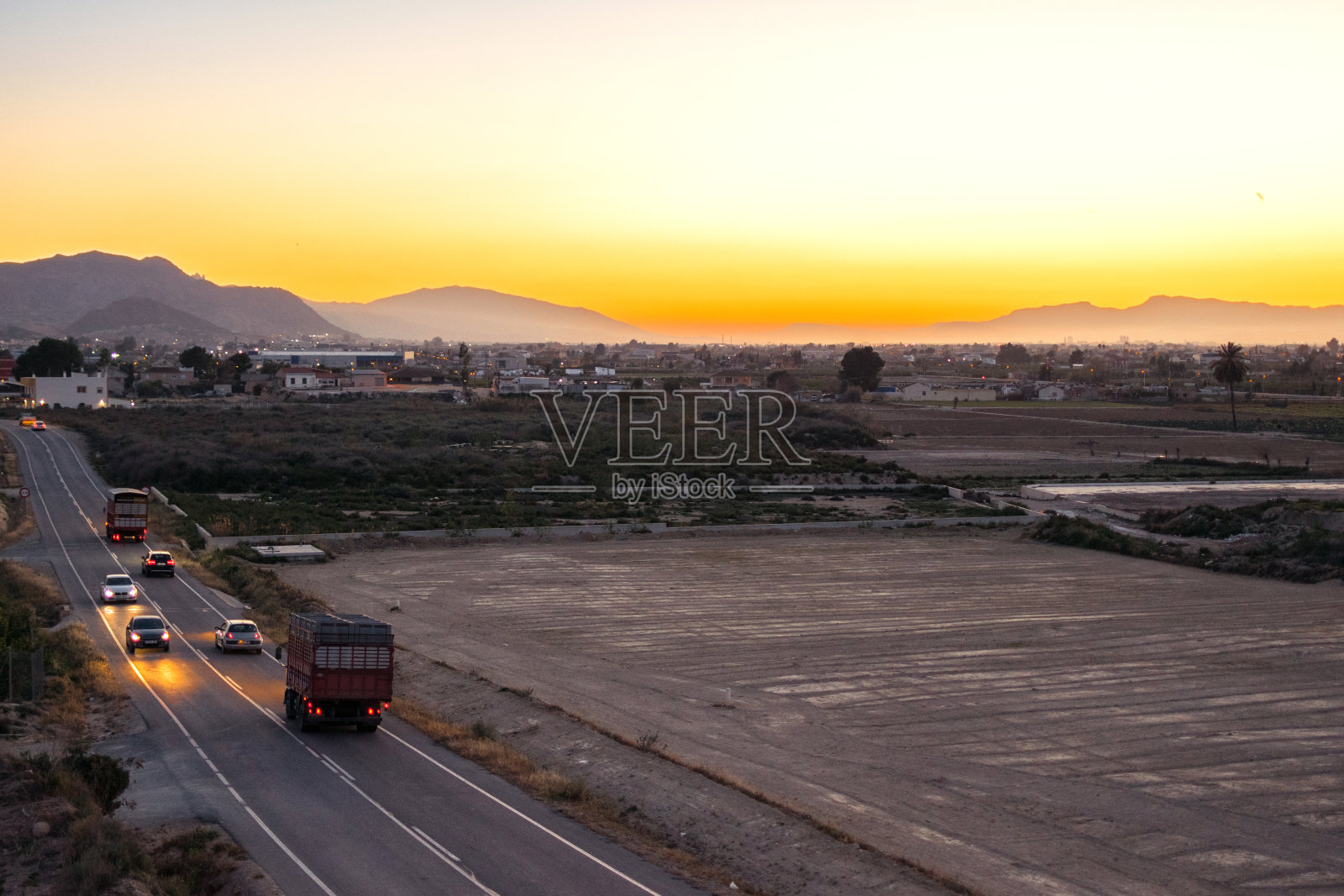 车辆在日落时行驶的景象。照片摄影图片