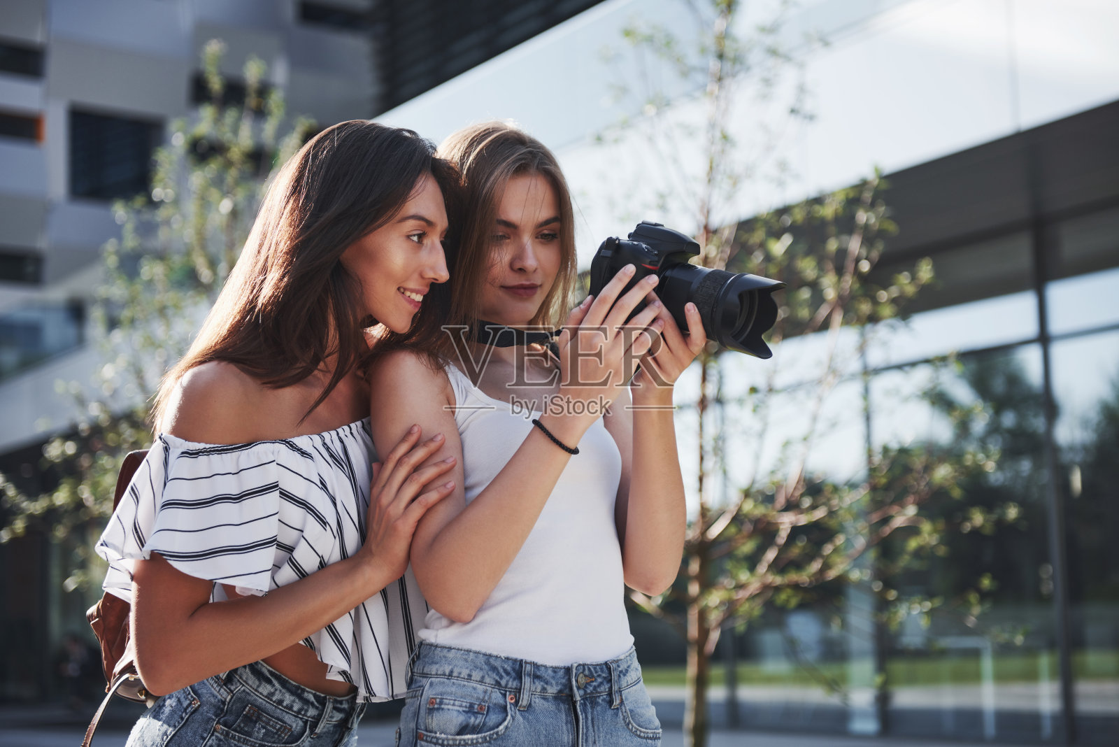 女孩的两个漂亮的朋友拿着相机一起拍照，走在城市里照片摄影图片