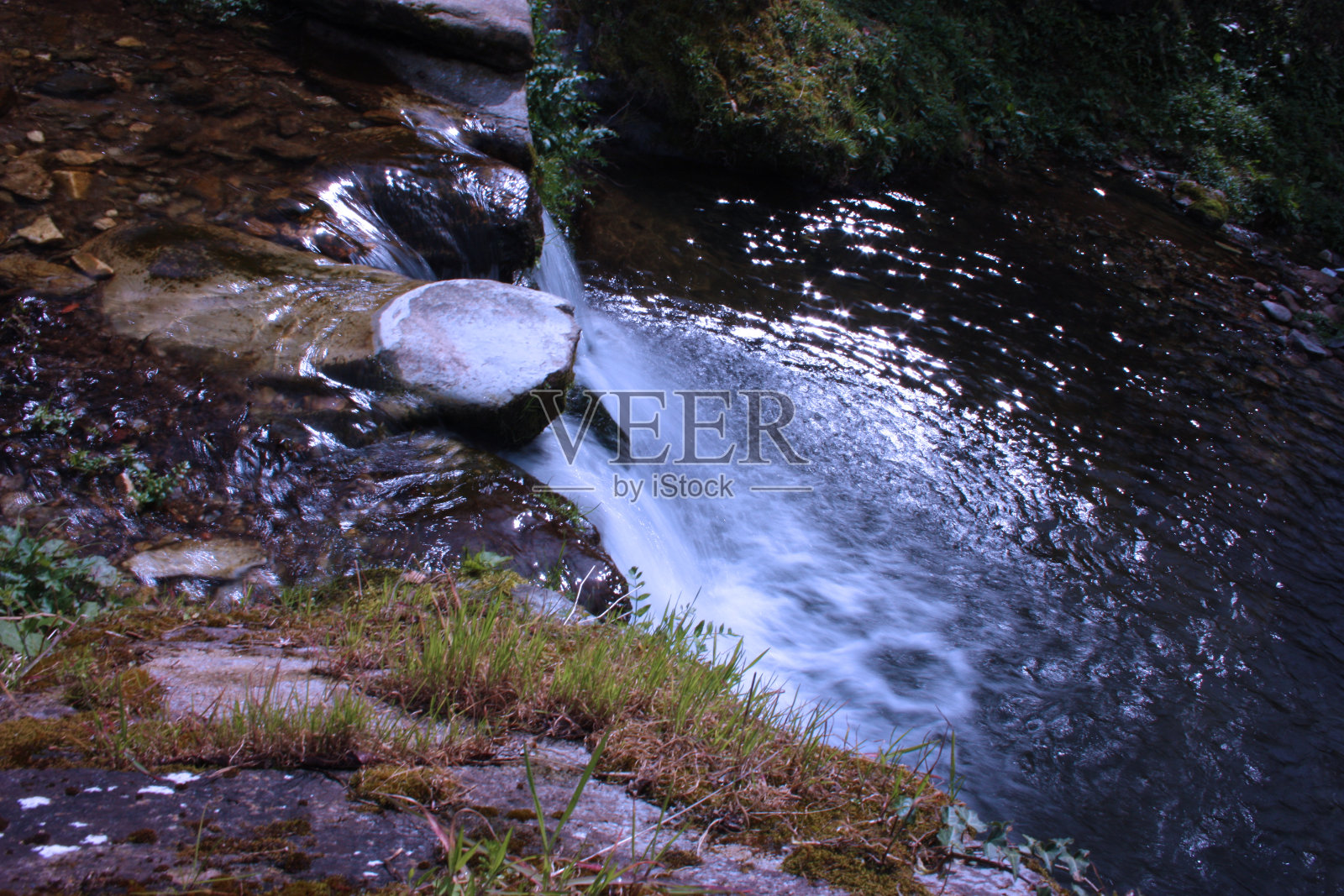 具有丝绸效果的水路。在树木繁茂的平原中央，从瀑布中流过的一条小河照片摄影图片