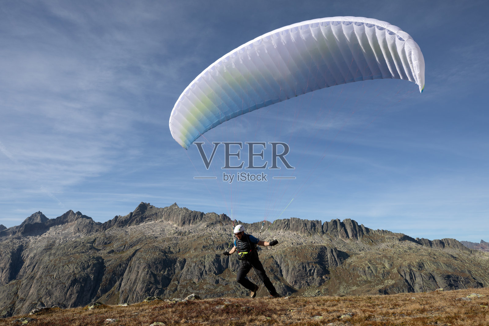 滑翔伞飞行员带着他的滑翔伞起飞，飞进瑞士阿尔卑斯山的山谷照片摄影图片