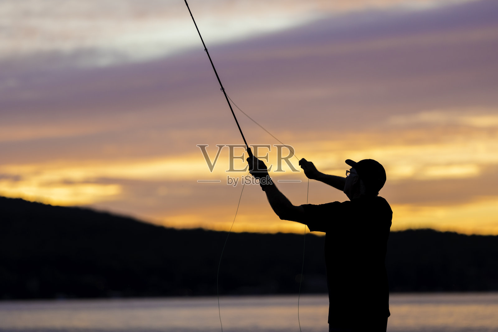 飞钓渔夫在日落湖上的剪影照片摄影图片