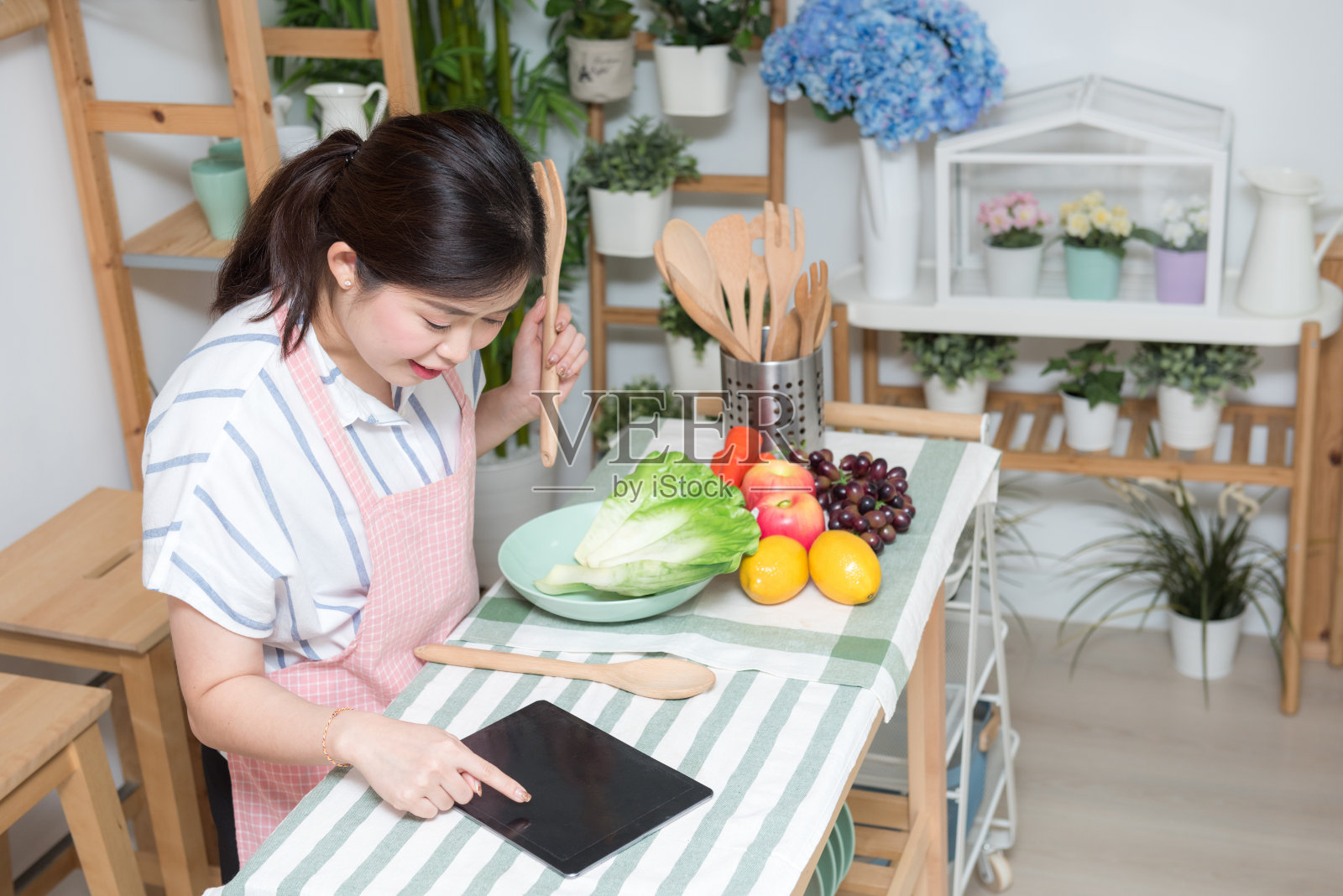 人类的手在厨房用触摸板烹饪的特写。健康饮食，素食和生活理念照片摄影图片