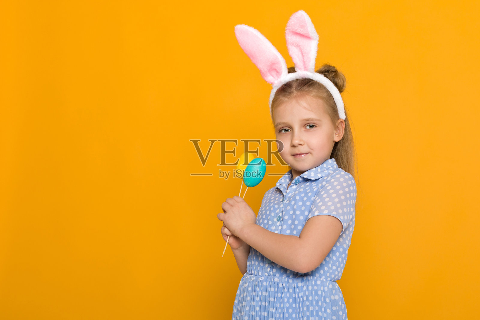 可爱的小女孩带着复活节兔子耳朵拿着五颜六色的蛋照片摄影图片