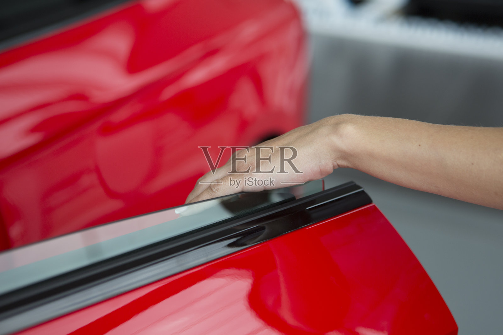 女人把手放在打开新的红色车门的背景上照片摄影图片