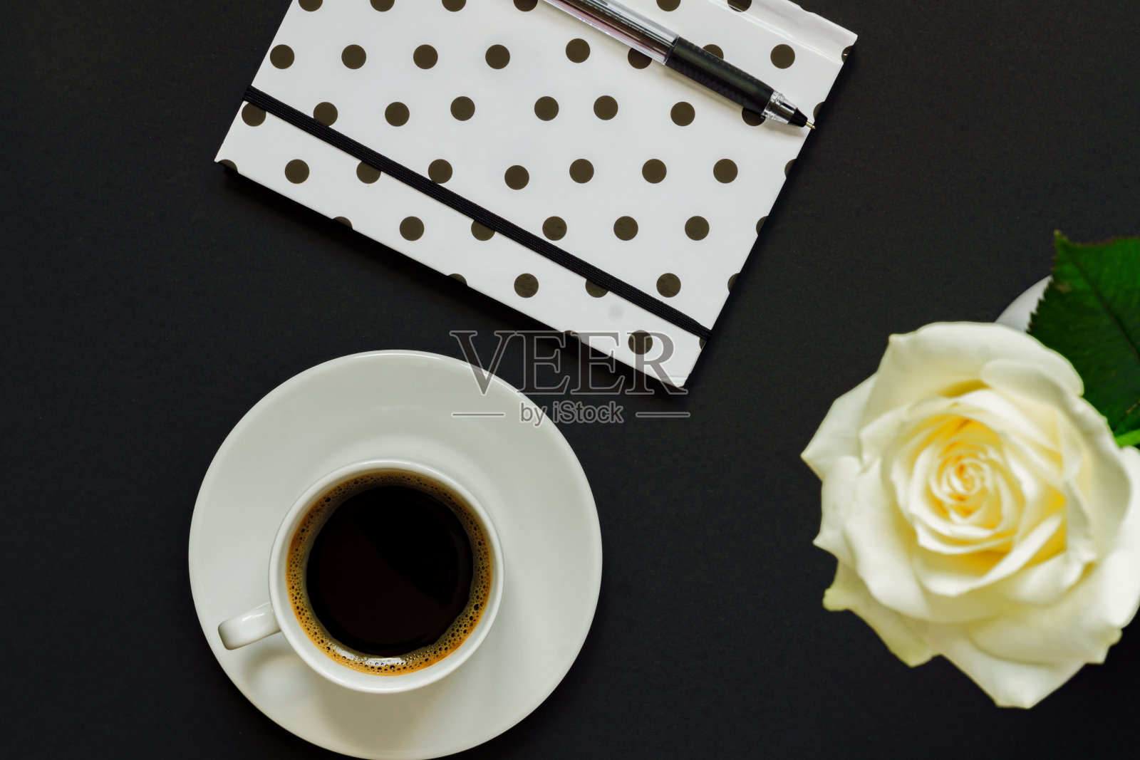 一杯黑咖啡，笔记本和白色玫瑰在黑色背景，俯视图，拷贝空间。照片摄影图片