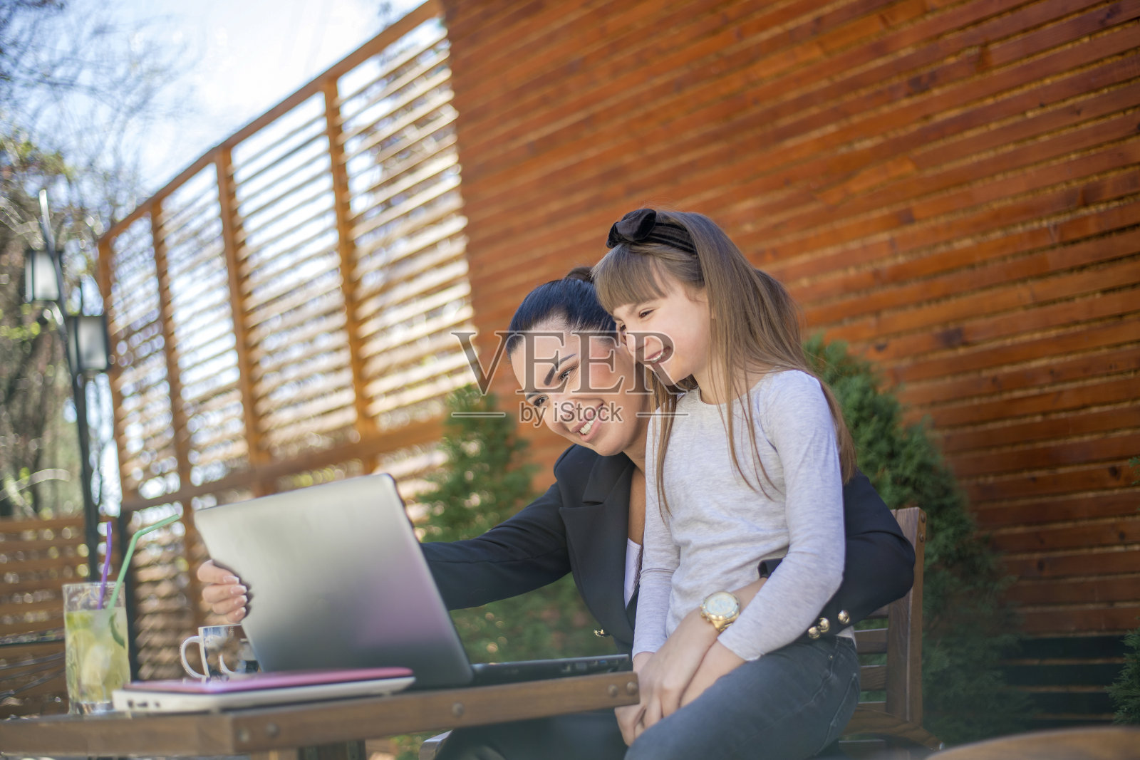 母亲和女儿在café平台上使用笔记本电脑照片摄影图片