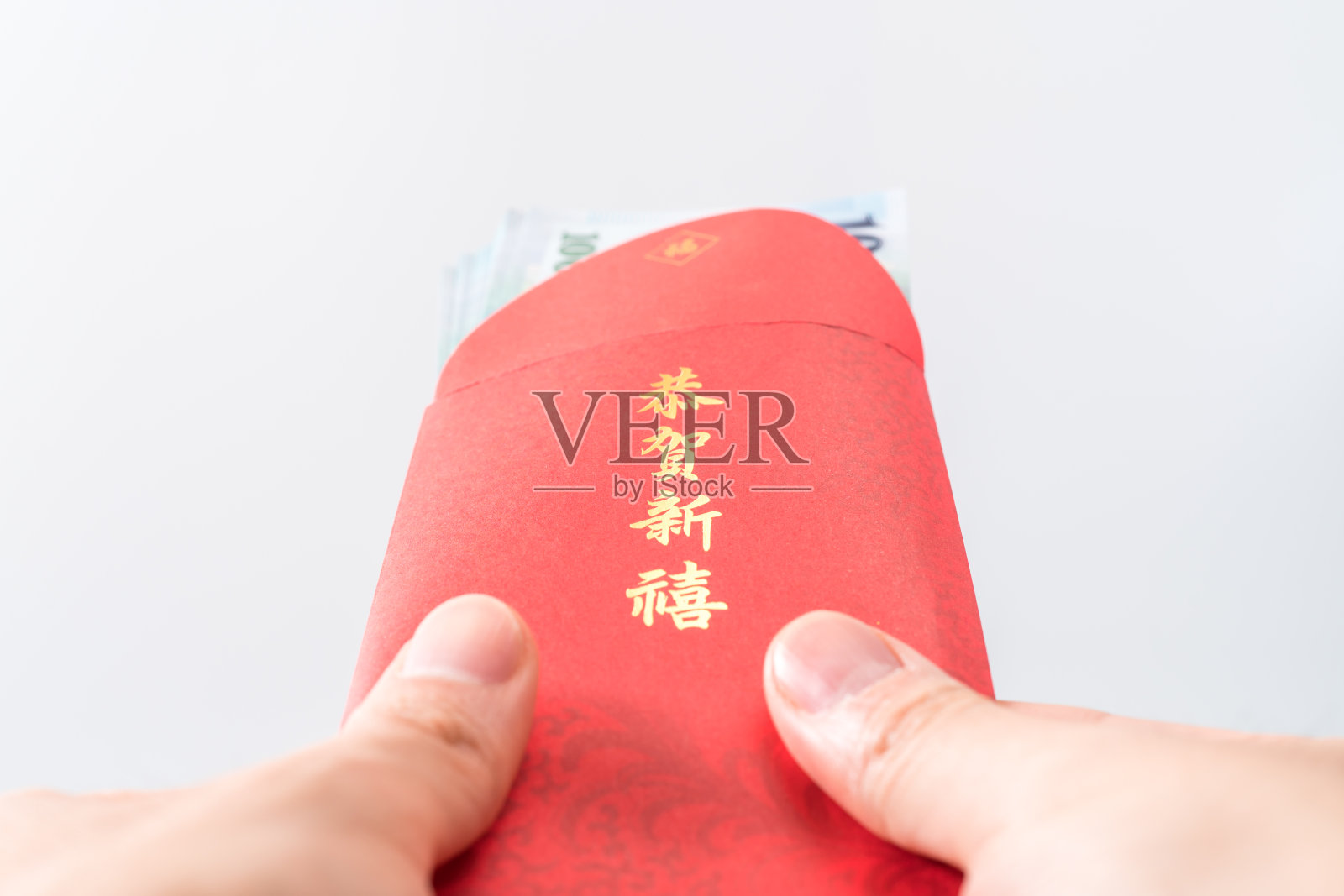 男人的手拿着中国的红包。中国新年的概念。(中文“Gōnghè xīnxǐ”的意思是“祝你财源广进”)照片摄影图片