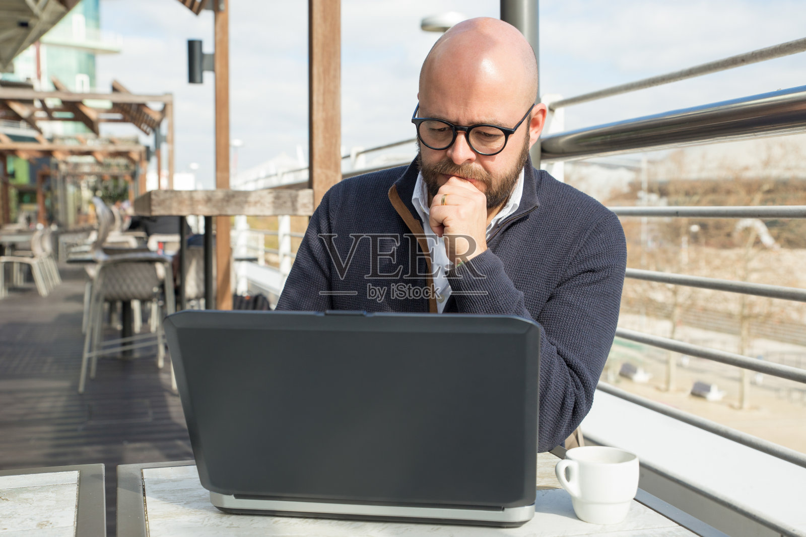 一个中年男子在街头咖啡馆里用笔记本电脑工作照片摄影图片