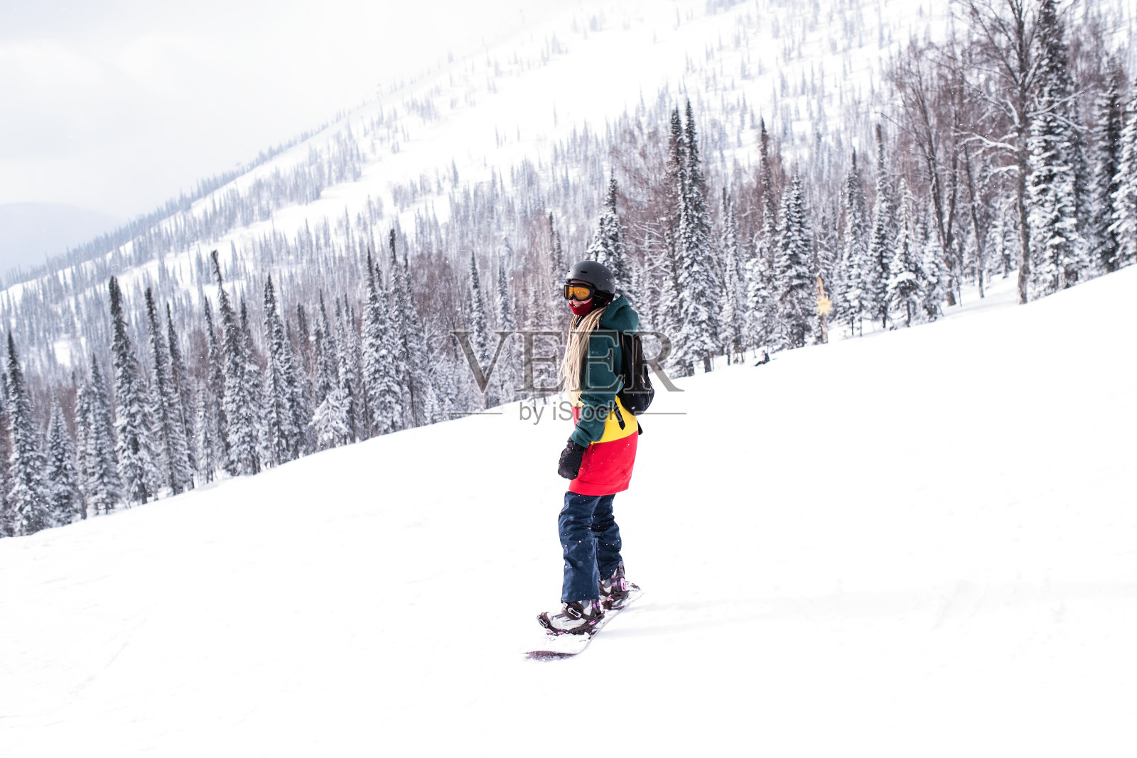 女自由滑雪板手在雪坡上骑滑雪板。照片摄影图片
